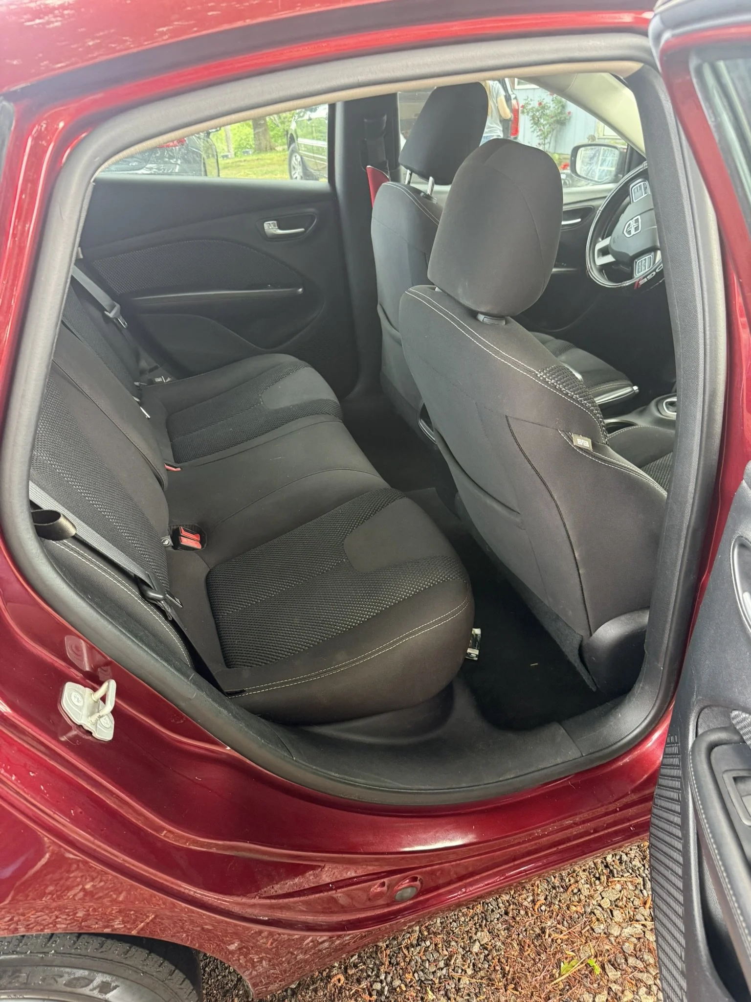The interior of a red car showing the front and rear seats, dashboard, and side door panels.