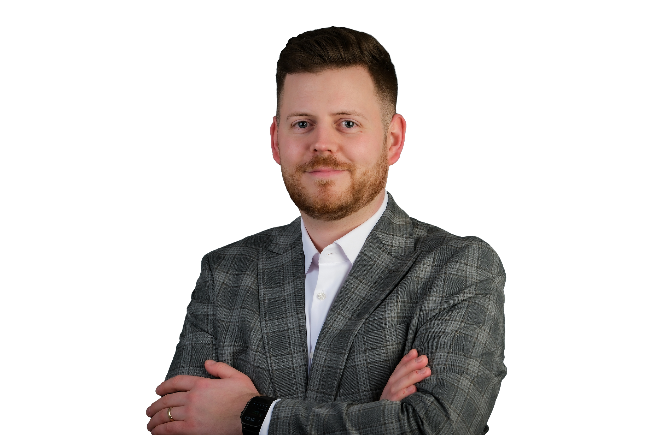 Ein Mann mit kurzen braunen Haaren, Vollbart und blauen Augen trägt einen grau-karierten Anzug und ein weißes Hemd. Er steht mit verschränkten Armen vor einem schwarzen Hintergrund.