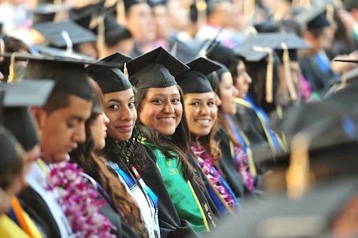Group of diverse graduates in caps and gowns at a graduation ceremony, smiling.