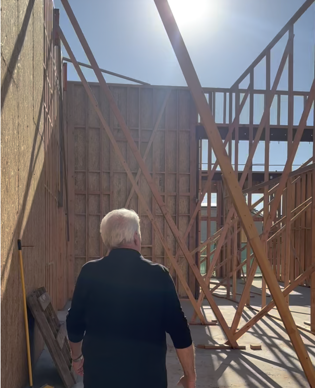 General contractor in Orange County California walking inside a house under construction with exposed wooden framing