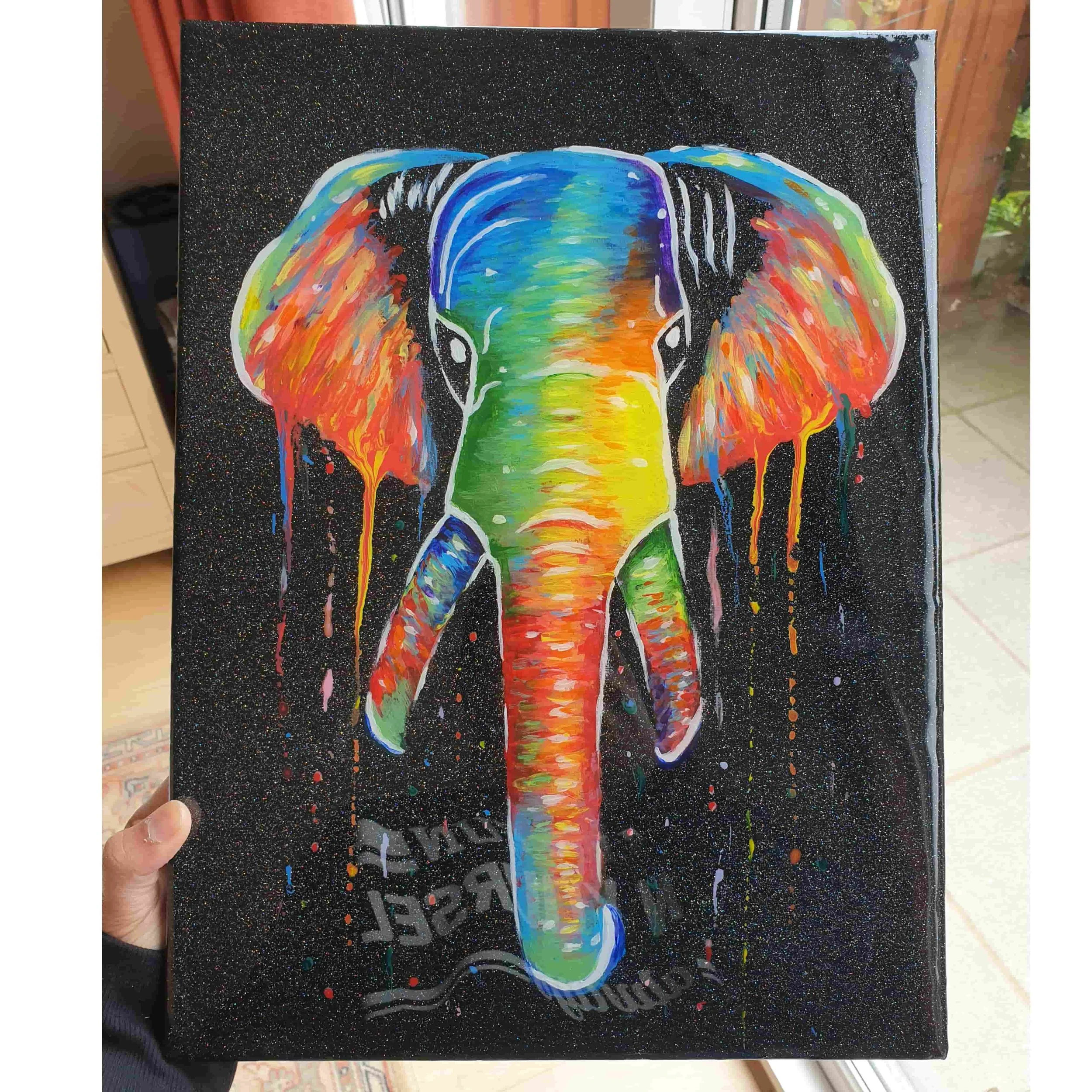 Colorful painting of an elephant with rainbow-colored trunk and ears, set against a black background with small colorful speckles.