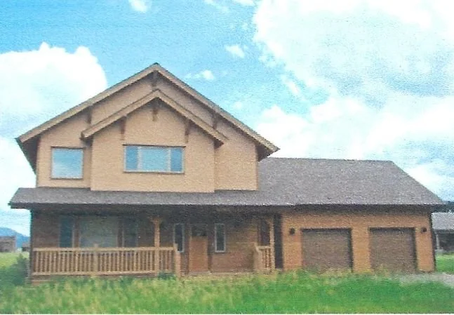 A two-story house with a brown exterior, front porch, and attached garage under a partly cloudy sky.