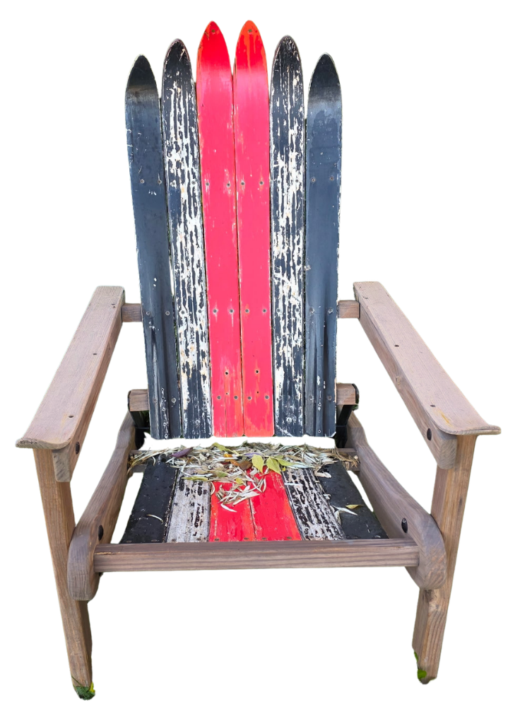A rustic wooden Adirondack chair painted with red and black colors, with peeling paint and fallen leaves on the seat.