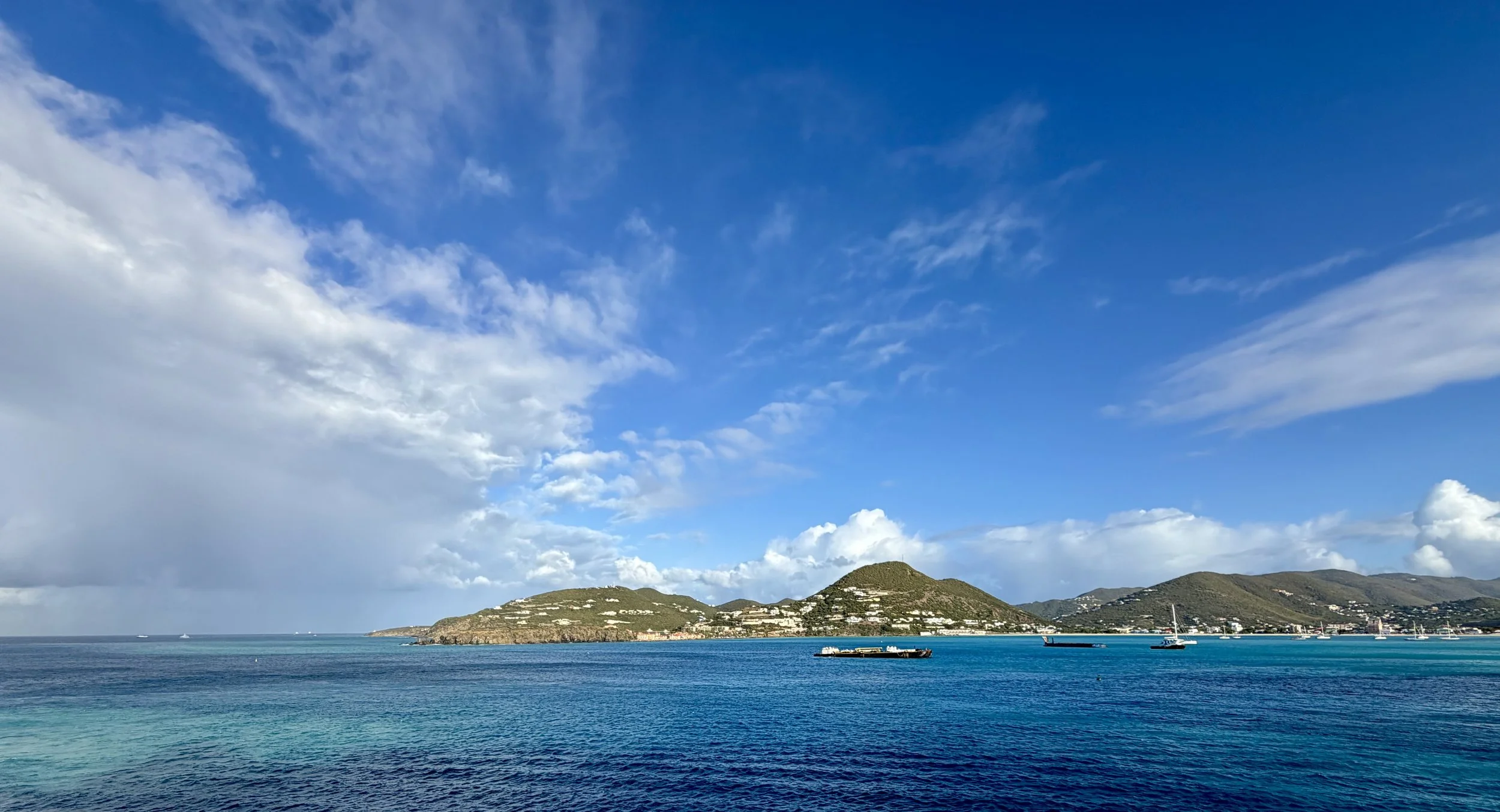Turquoise bay off St. Thomas, US Virgin Islands, with green hillside town, sailboats at anchor, and blue sky