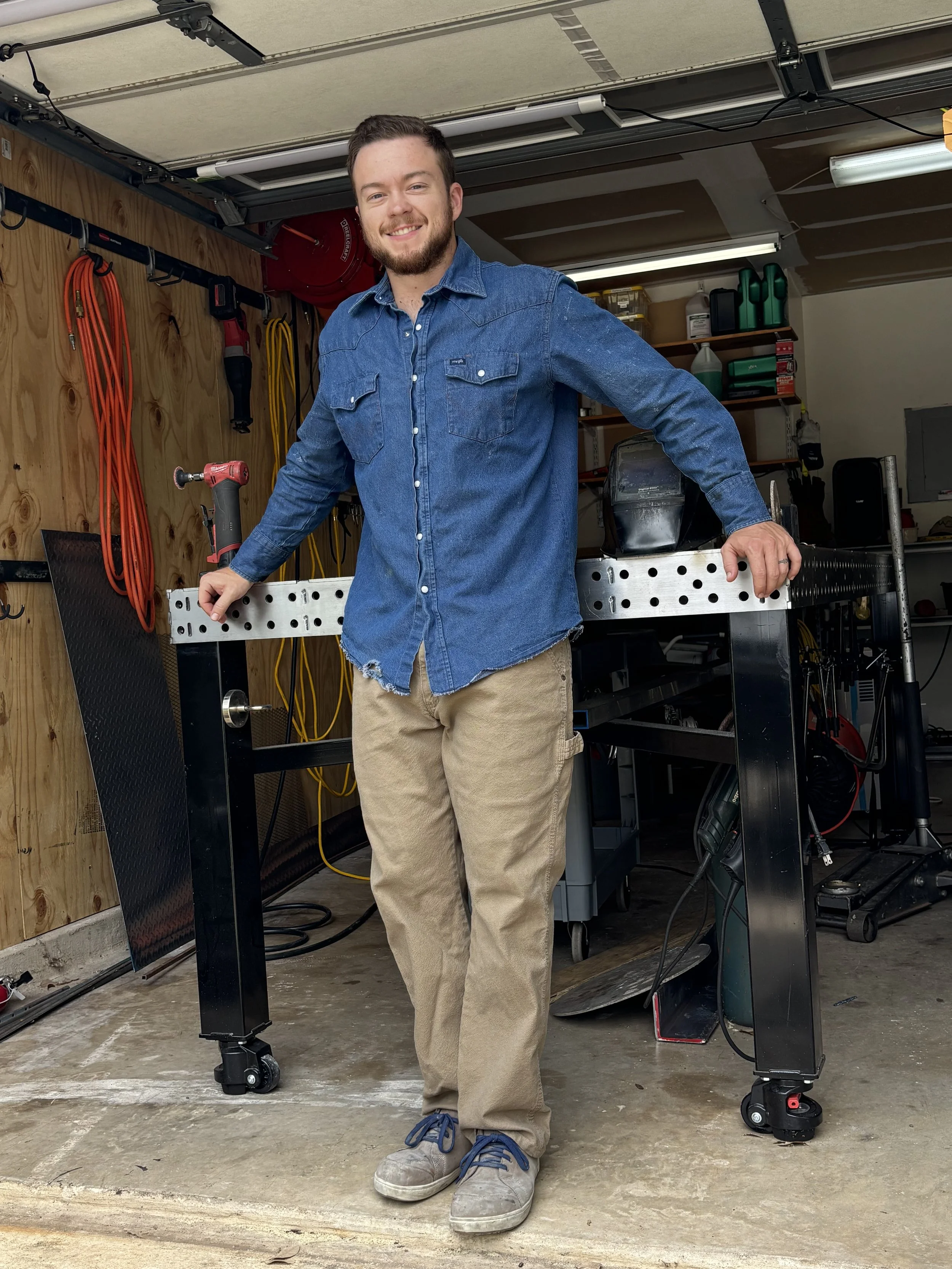 Aerospace welder and owner of Remington Welding standing in his shop, surrounded by welding equipment and tools.