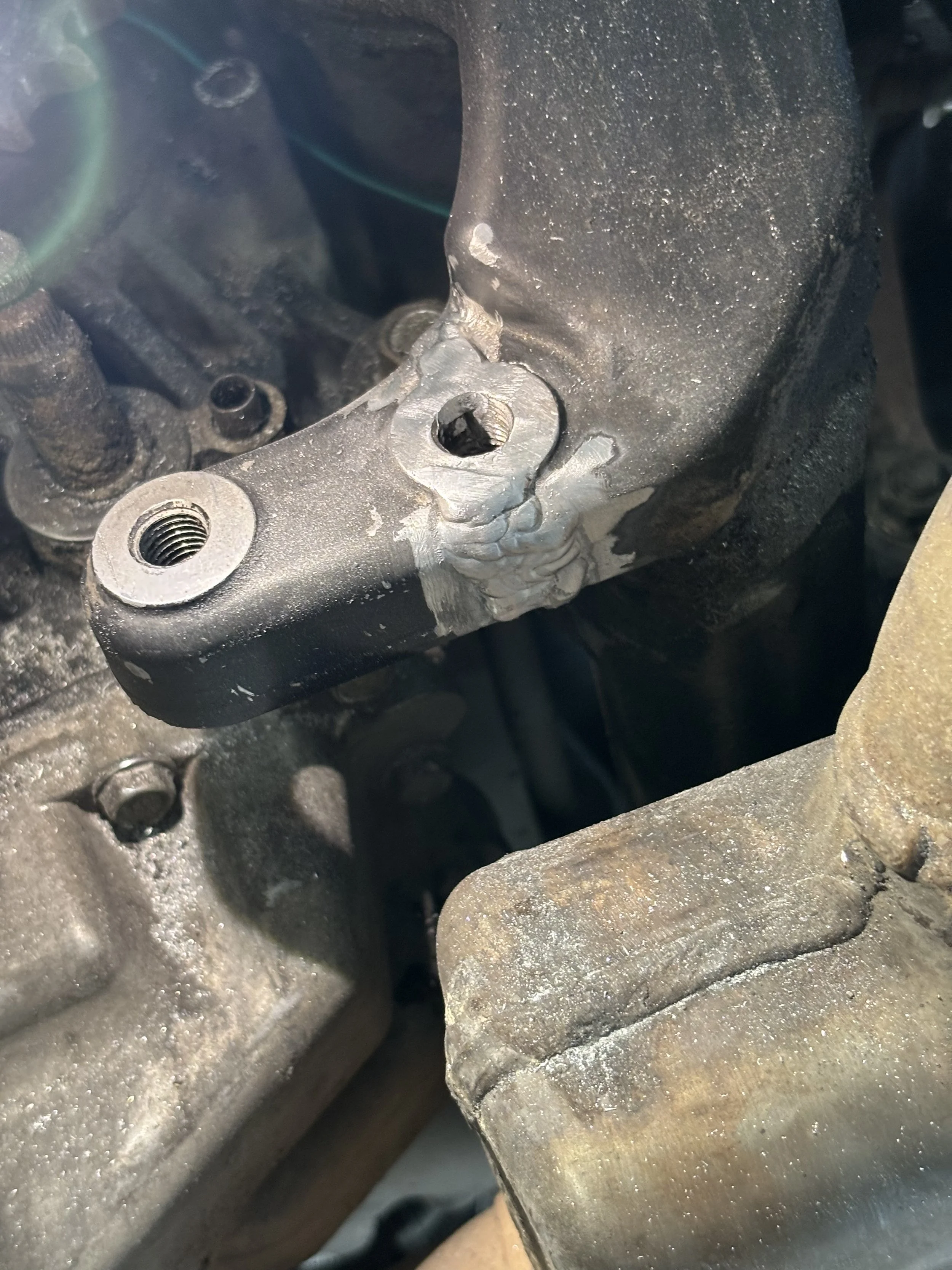 Close-up of a metallic component with a damaged or stripped screw hole and surrounding area showing signs of wear and corrosion.