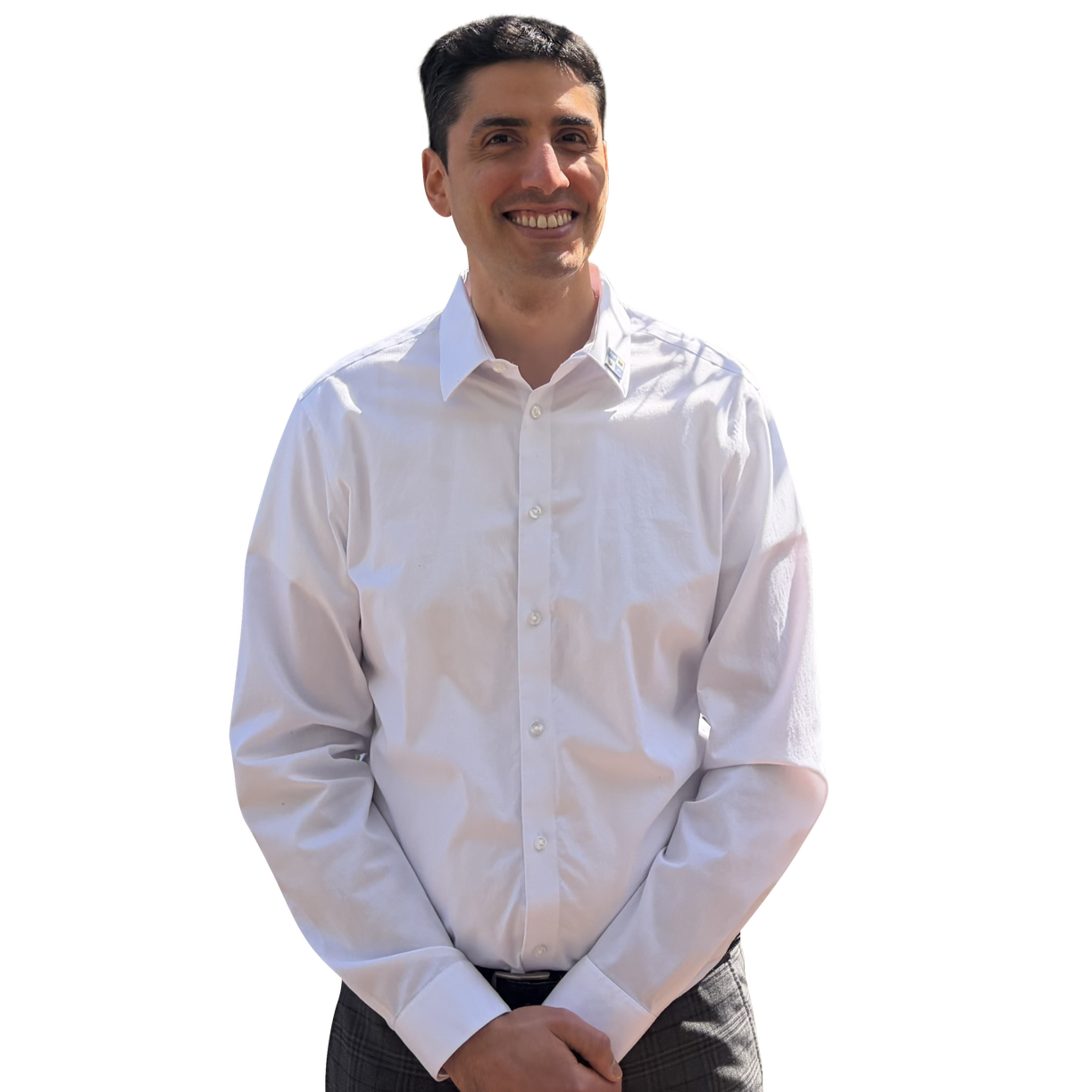 Smiling man in a white dress shirt with a collar and plaid pants, standing outdoors with a confident posture.