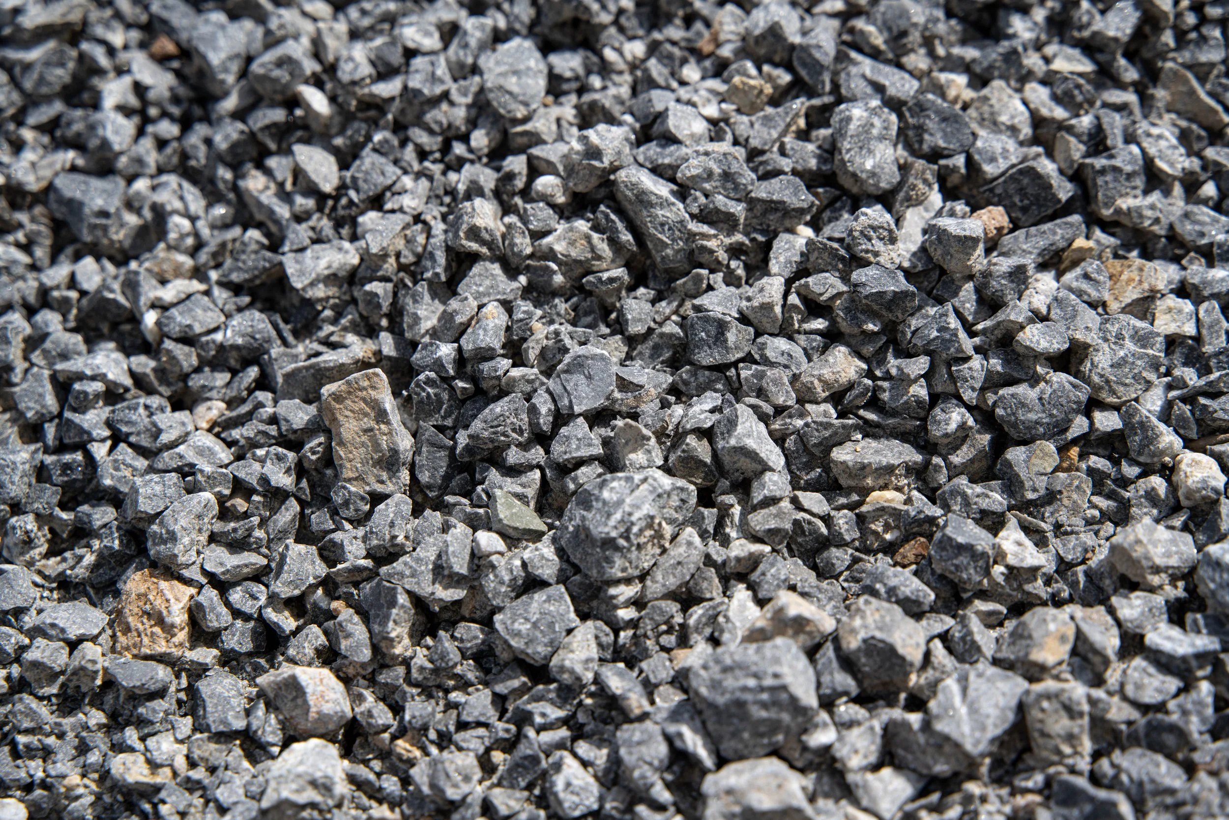 Close-up of small gray and black gravel stones scattered on the ground.
