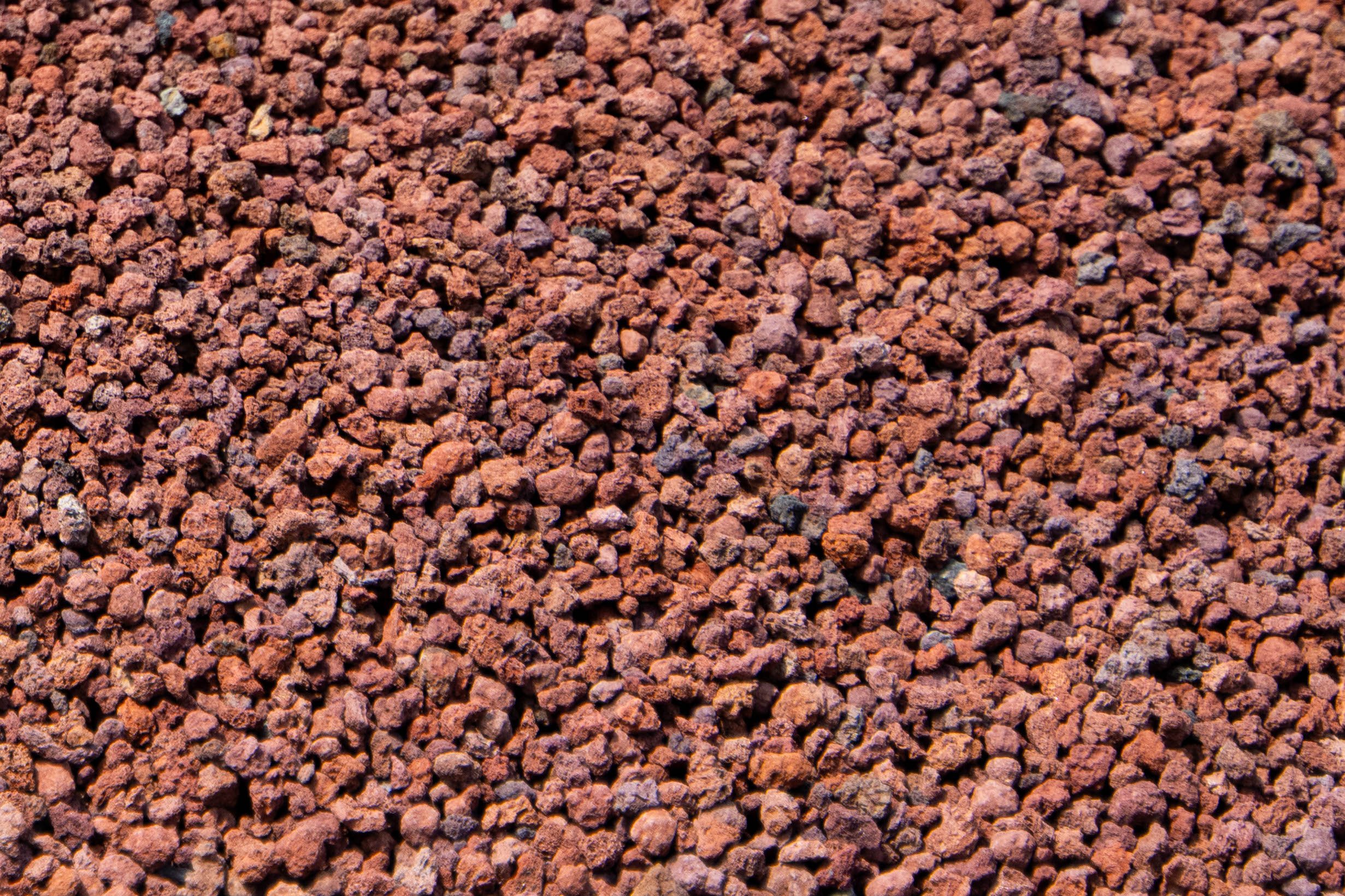 Close-up photograph of a textured surface composed of small reddish-brown gravel or crushed stone.