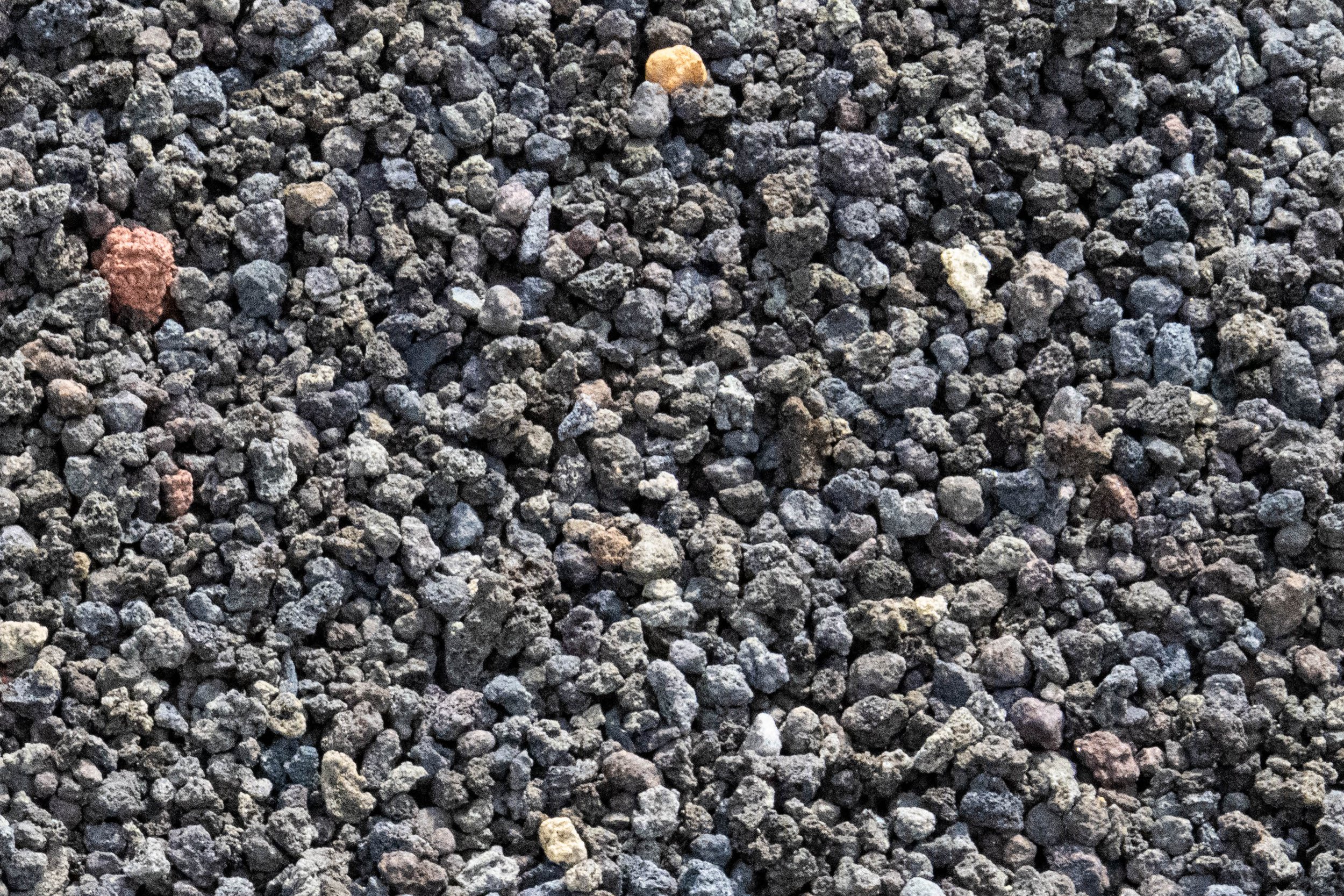 Close-up view of dark gray gravel with a few scattered lighter and reddish stones.
