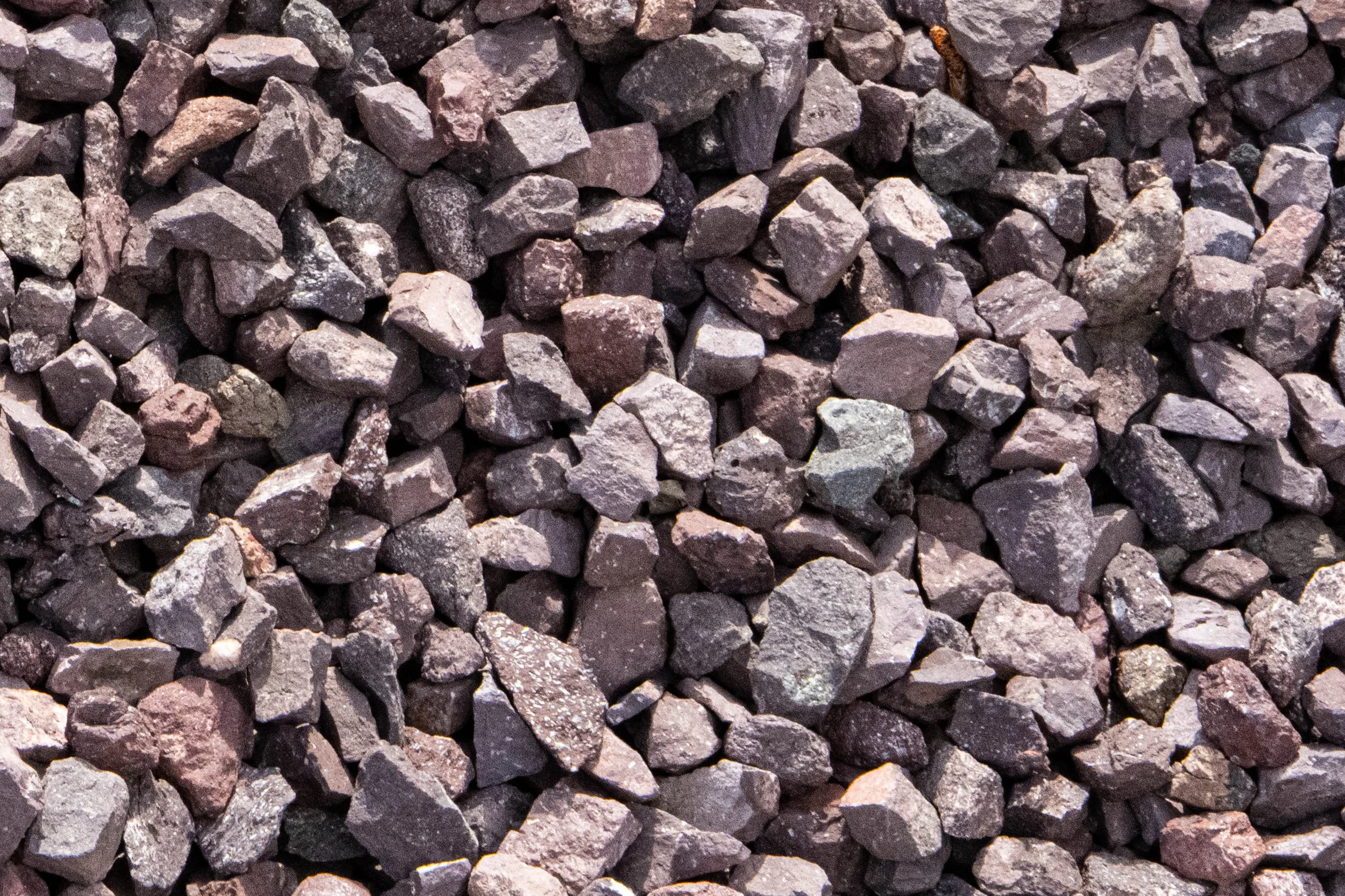 Close-up view of small, irregularly shaped gravel stones in various shades of gray and purple.