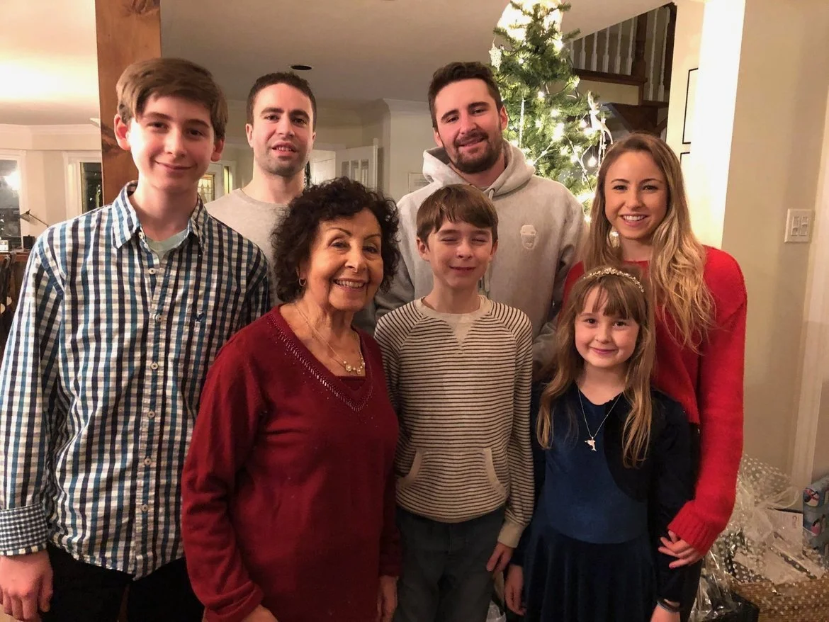 A family group photo around a decorated Christmas tree in a cozy home.