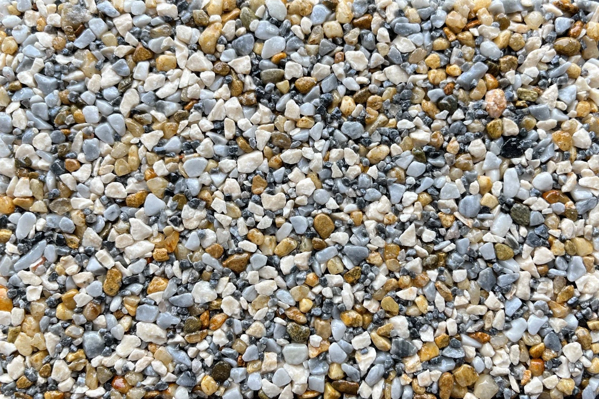 Close-up of a surface covered with small, multicolored pebbles and stones in shades of white, gray, brown, and black.