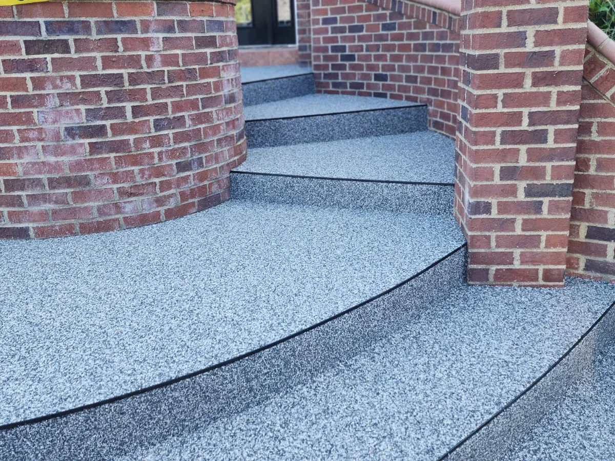 Concrete stairs with black outlines leading up to a brick building entrance.