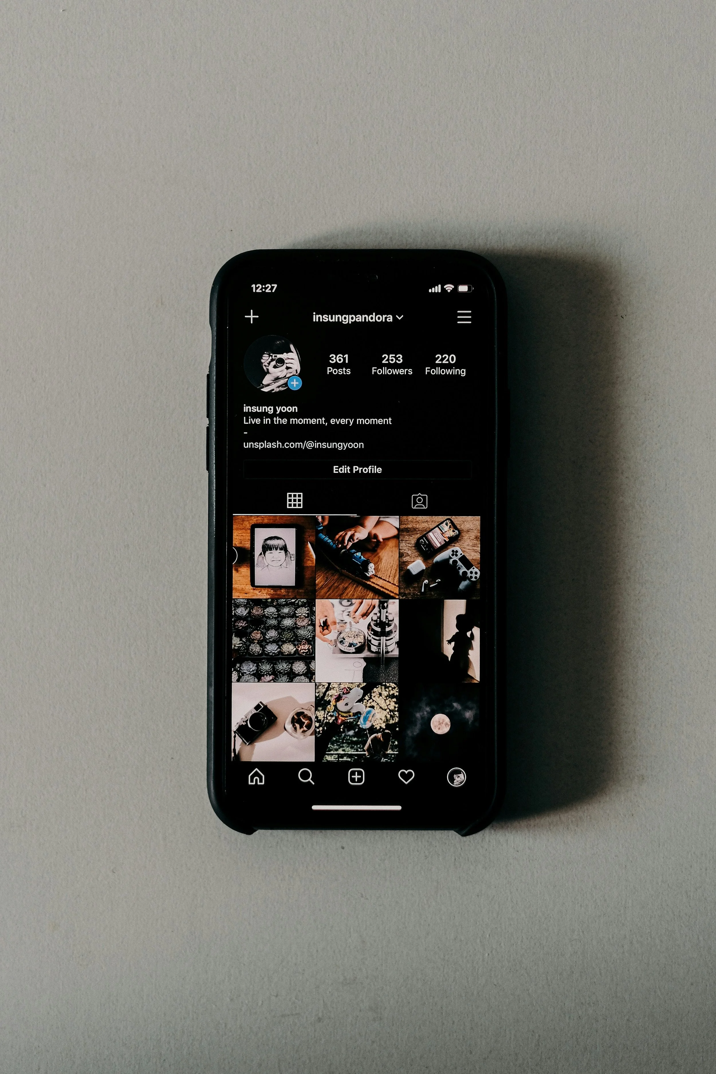 Close-up of a smartphone displaying an Instagram profile on a light gray surface.