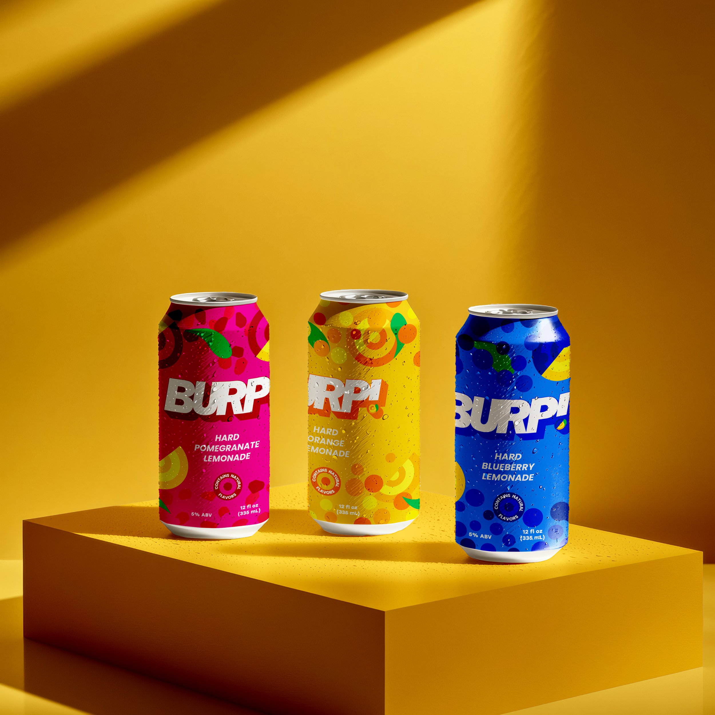 Three cans of flavored lemonade with colorful abstract designs on a yellow surface against a yellow background.