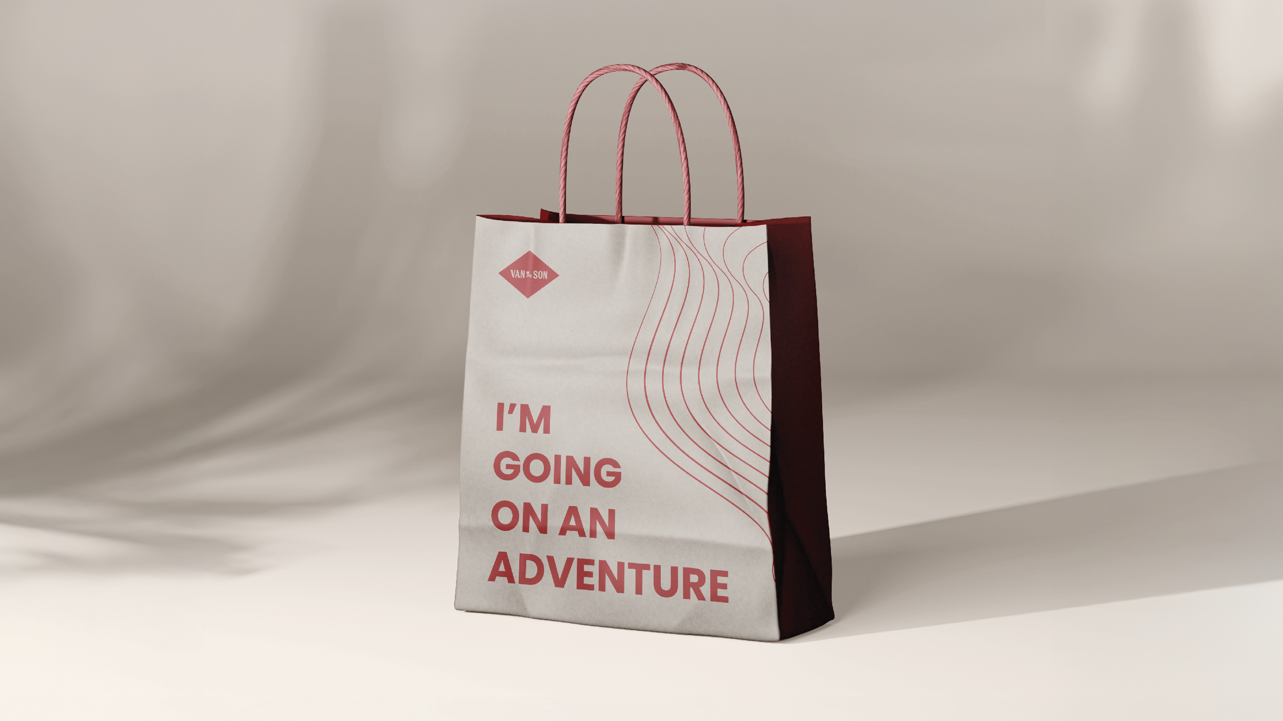 A shopping paper bag with pink handles and a design that includes the text "I'M GOING ON AN ADVENTURE" and a pink diamond-shaped logo that reads "VAN & SON".