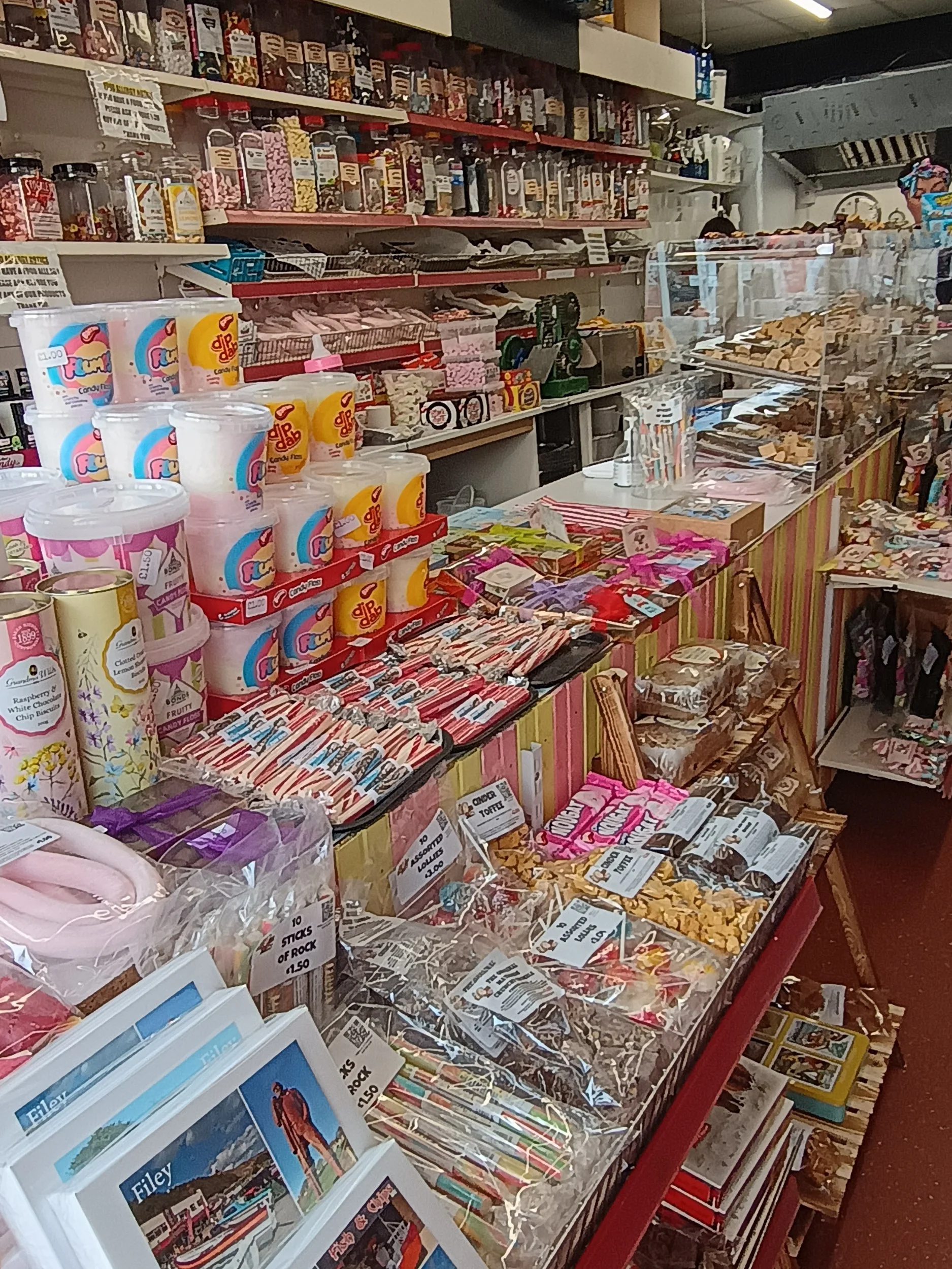 A store display with various sweets, snacks, and candies, including chocolate bars, jars of candies, and bags of snack foods.