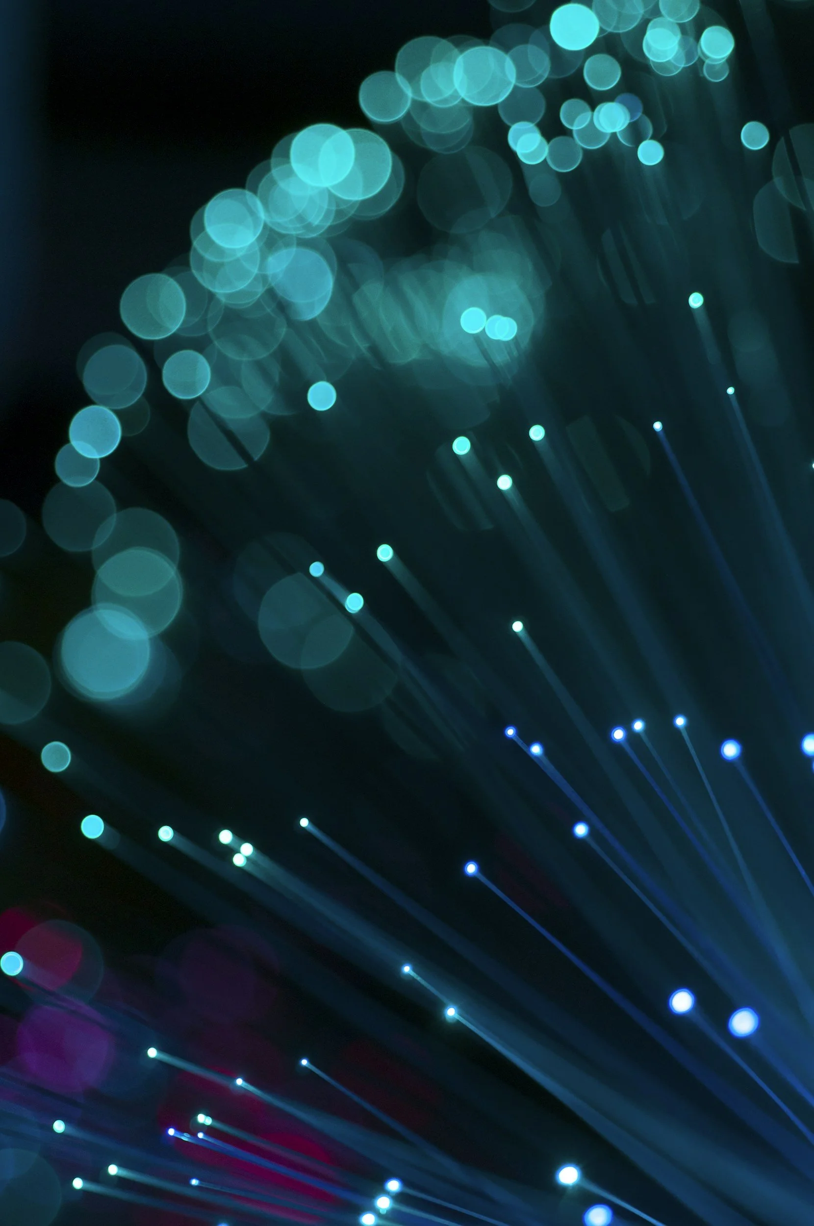 Blurred light streaks and bokeh in blue, teal, and purple colors at night, creating an abstract pattern.