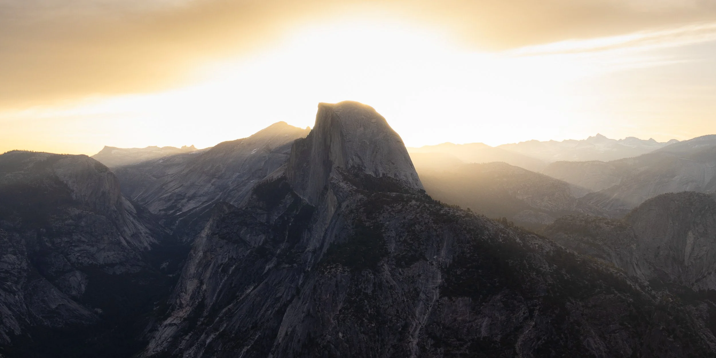 Sunset over the mountains with Half Dome peak in Yosemite National Park.