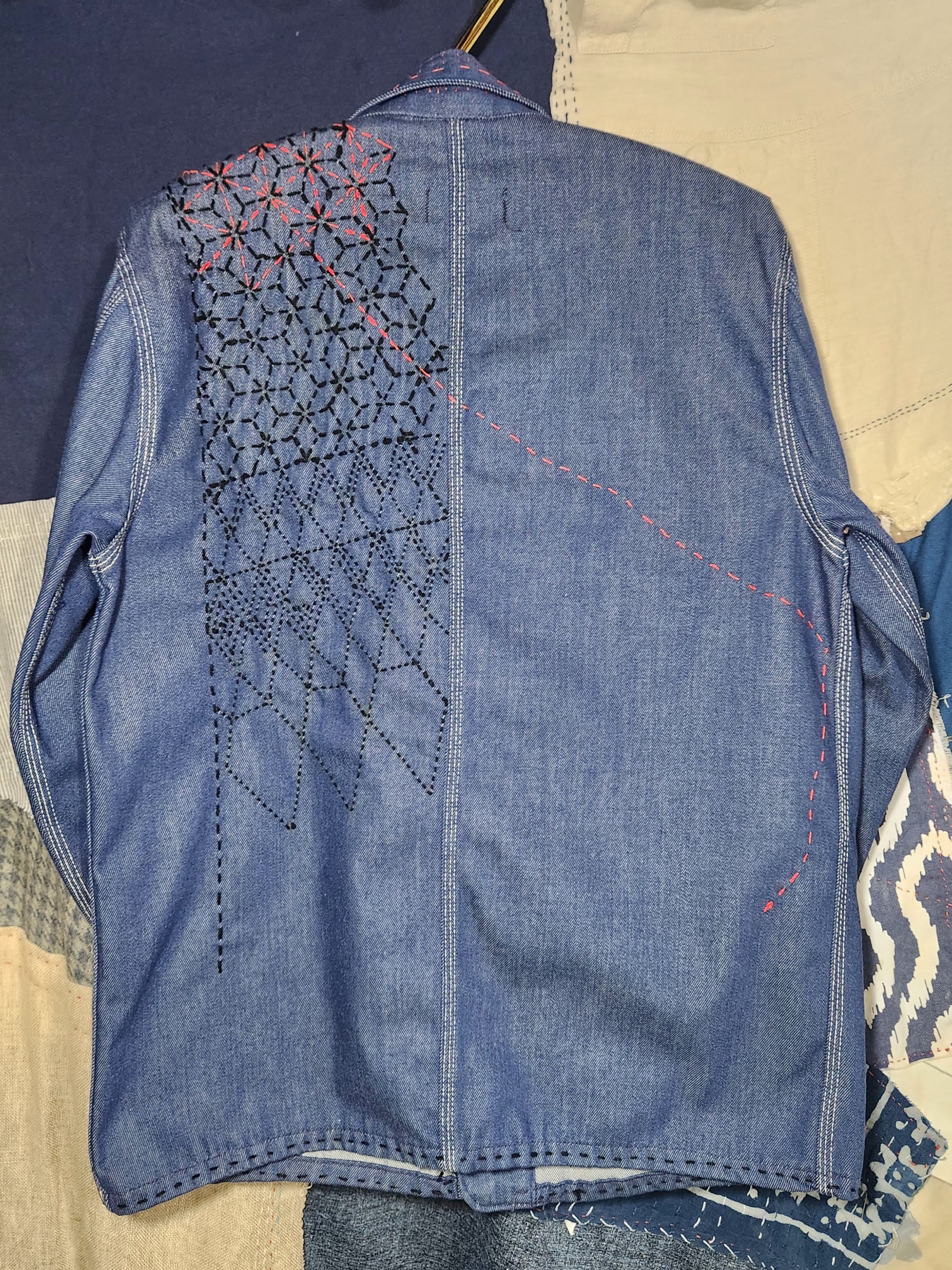 The pattern from the front carries over the left shoulder and turns from red to black, except for one rogue thread.