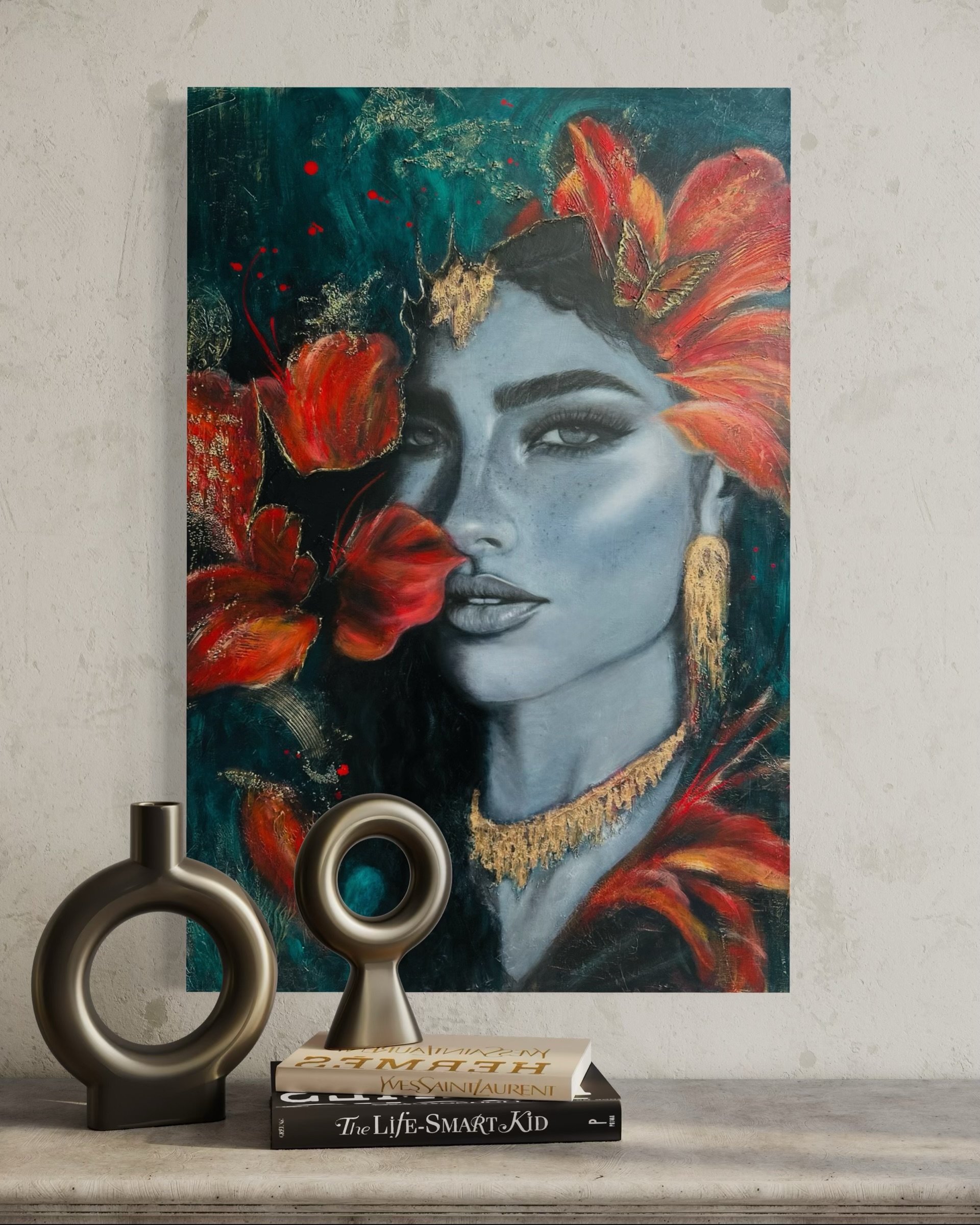 A modern still life arrangement featuring a colorful abstract portrait of a woman with vibrant red and orange foliage on her head, a black-and-white artistic book titled 'The Life-Smart Kid,' a collection of fashion books, and two decorative circular sculptures on a wooden surface against a neutral wall.