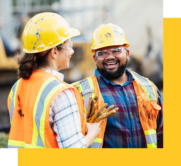Photo of two workers in hard hats and visibility vests smiling together
