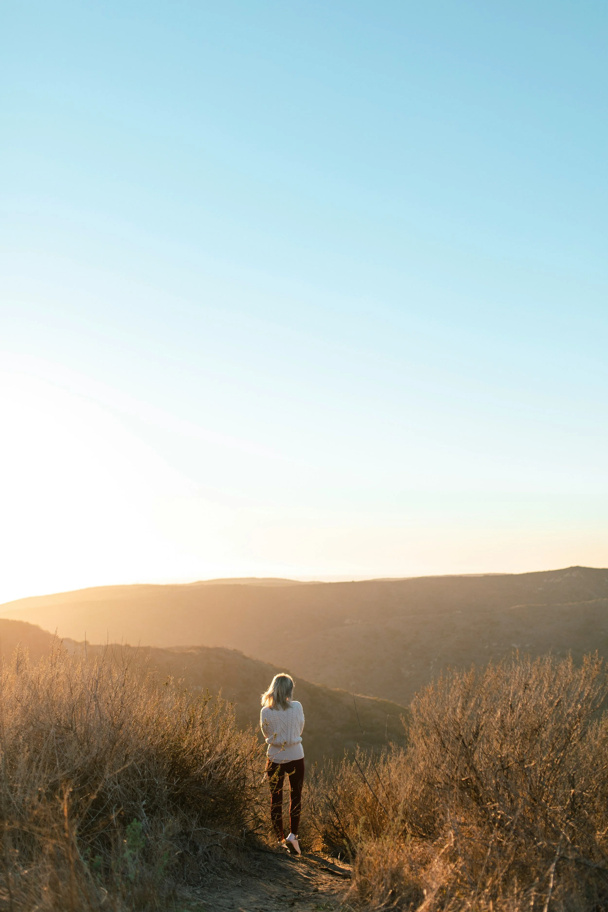 Woman walking on a nature path in the sun.