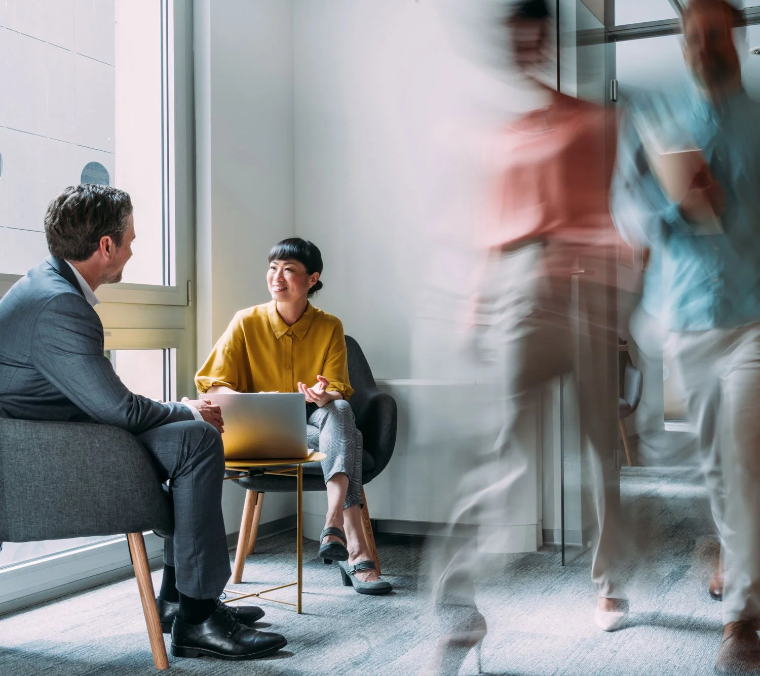 A man and woman of different backgrounds collaborating in a busy tech office, representing the high-impact, diverse hires Growth Mode Talent Partners delivers for fast-growing startups.