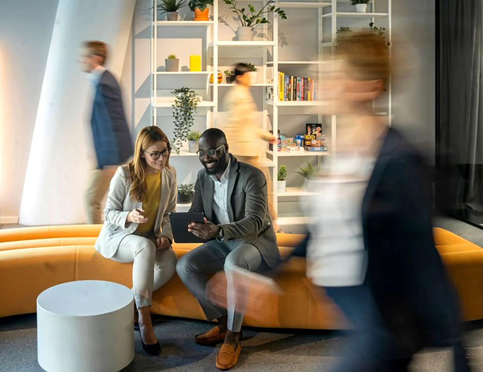 A man and woman of different backgrounds collaborating in a busy tech office, representing the high-impact, diverse hires Growth Mode Talent Partners delivers for fast-growing startups.