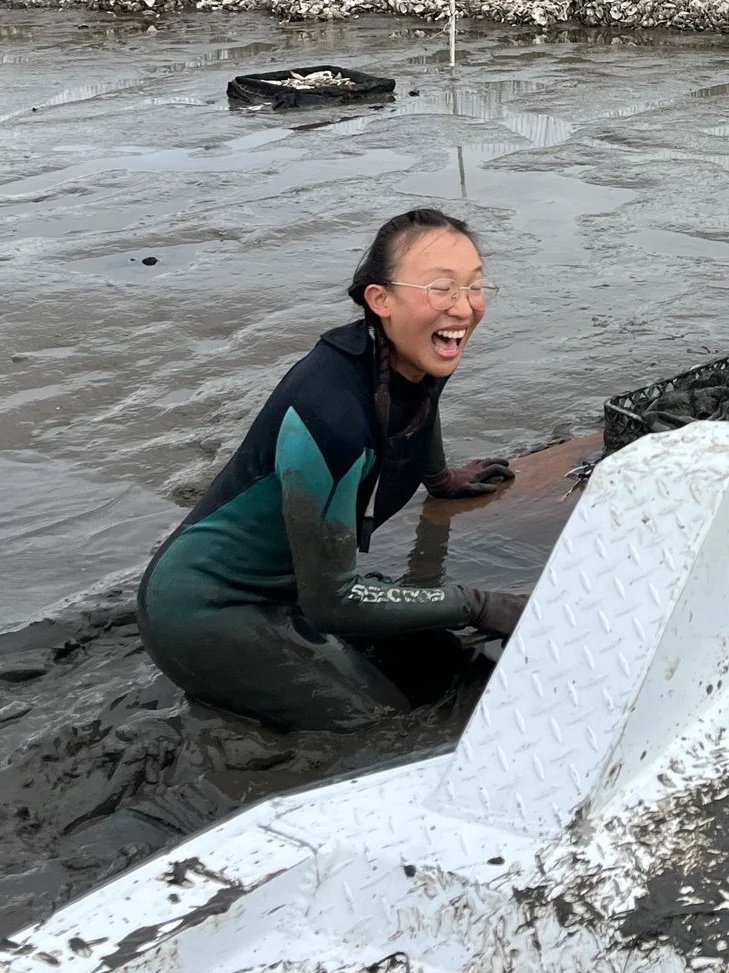Lillian in a wetsuit in a mudflat