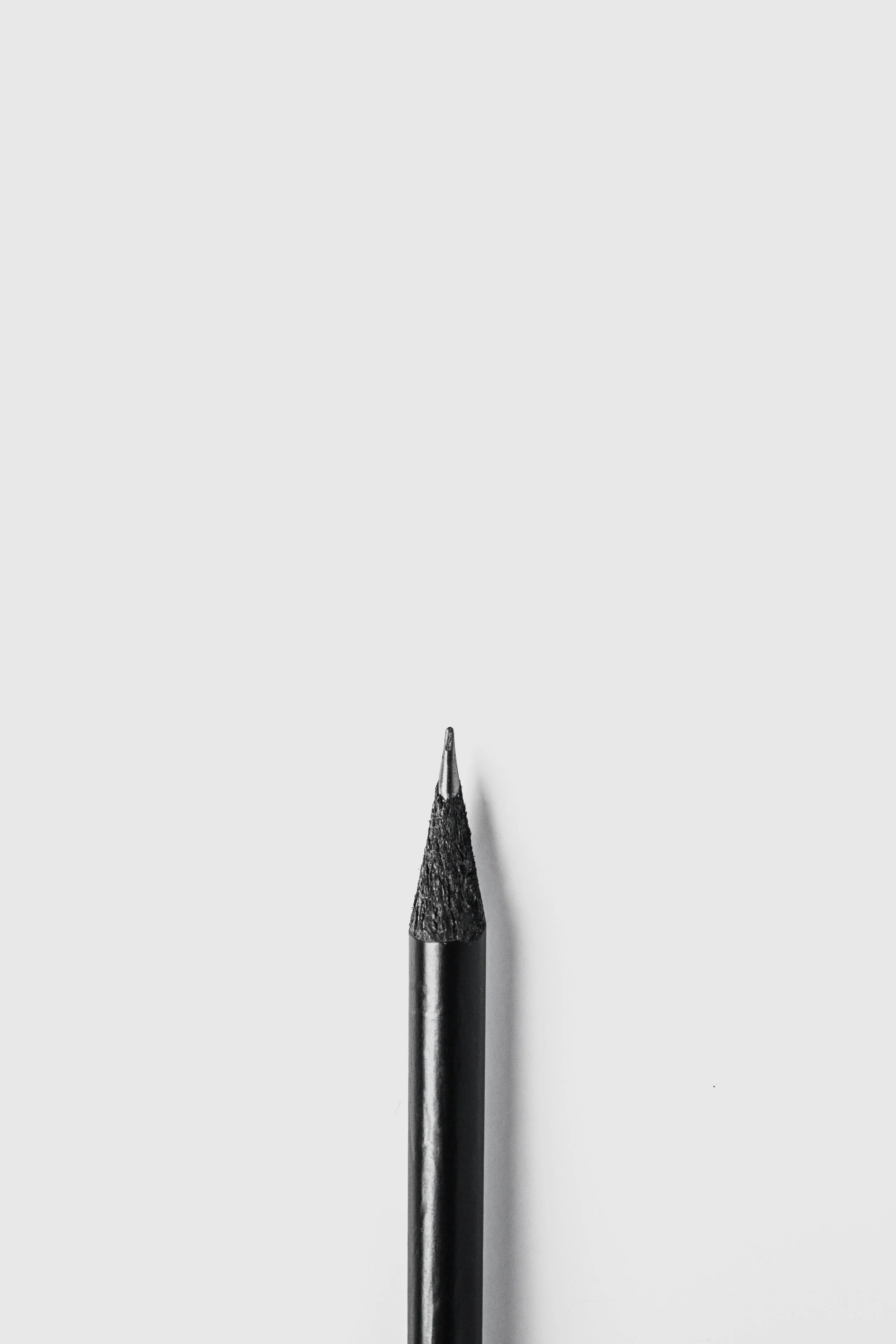 Close-up of a black sharpened pencil tip on a white background.