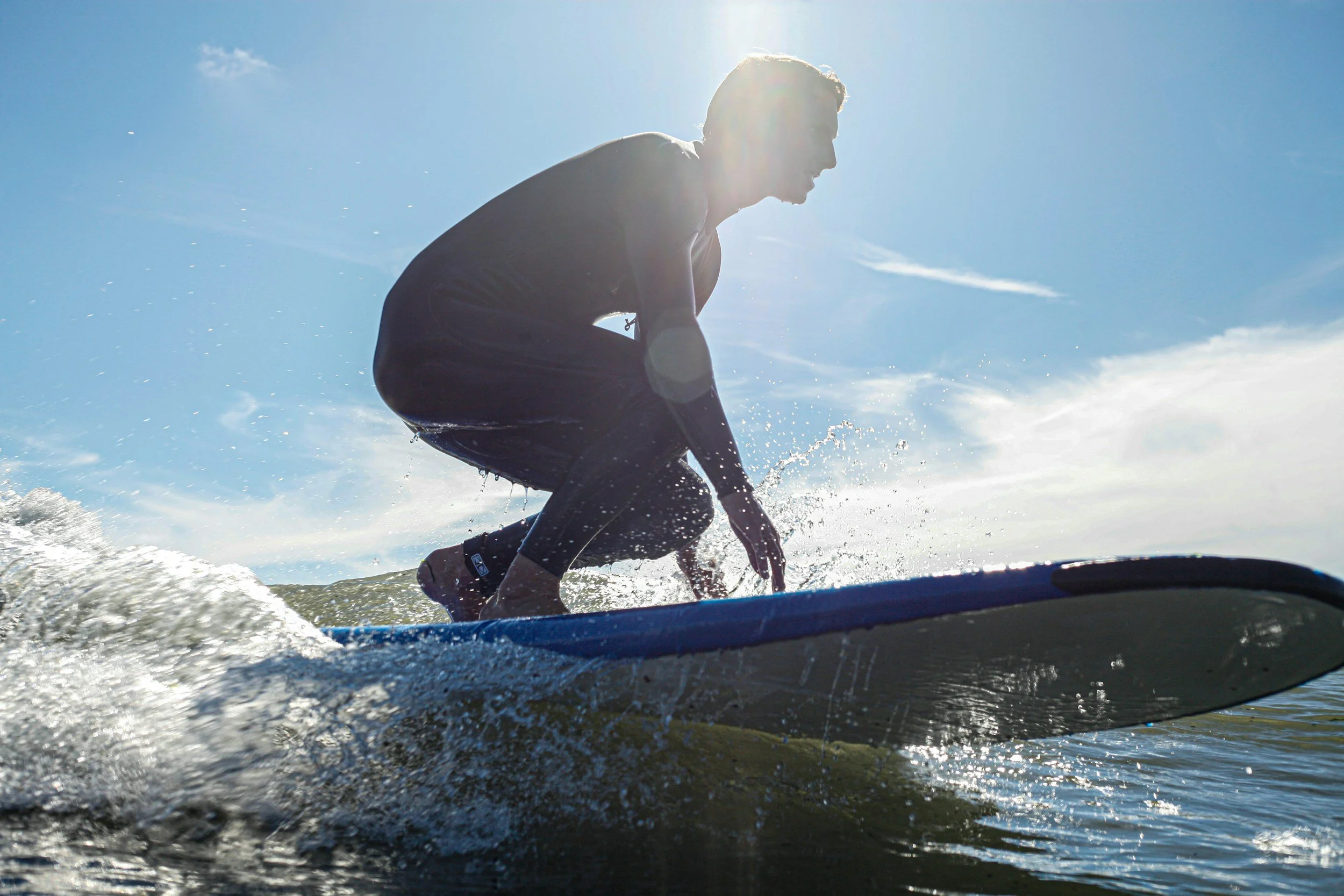 Surfer standing up on a small wave on a beginner surfboard