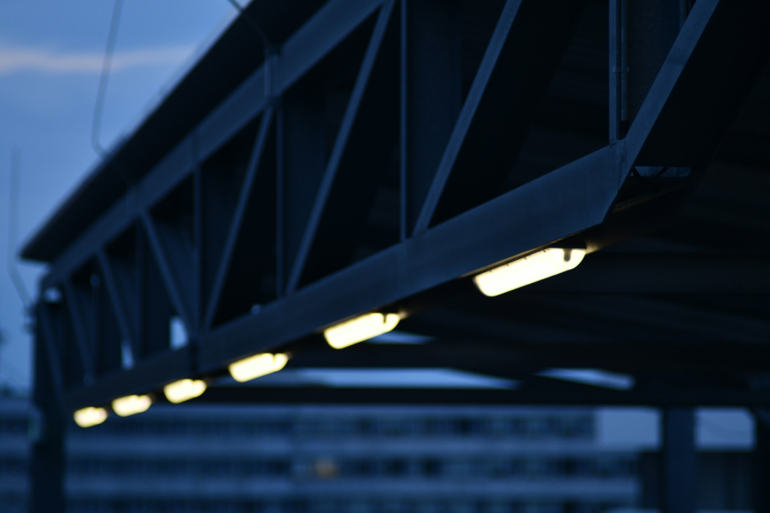 Close-up of a bridge with illuminated yellow lights underneath, showcasing steel beams and structure.
