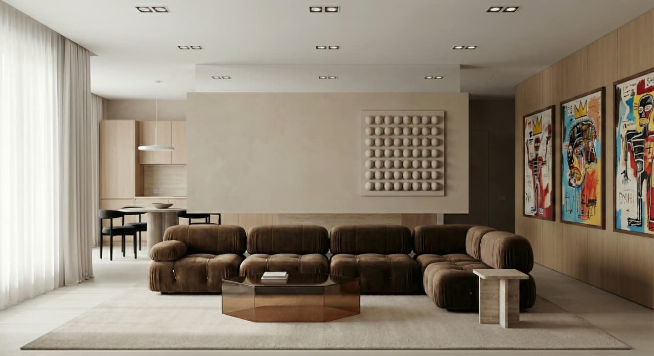 Sala de estar moderna con sillón grande de color marrón, mesa de centro de madera, paredes decoradas con arte abstracto y una escultura de bolas blancas.