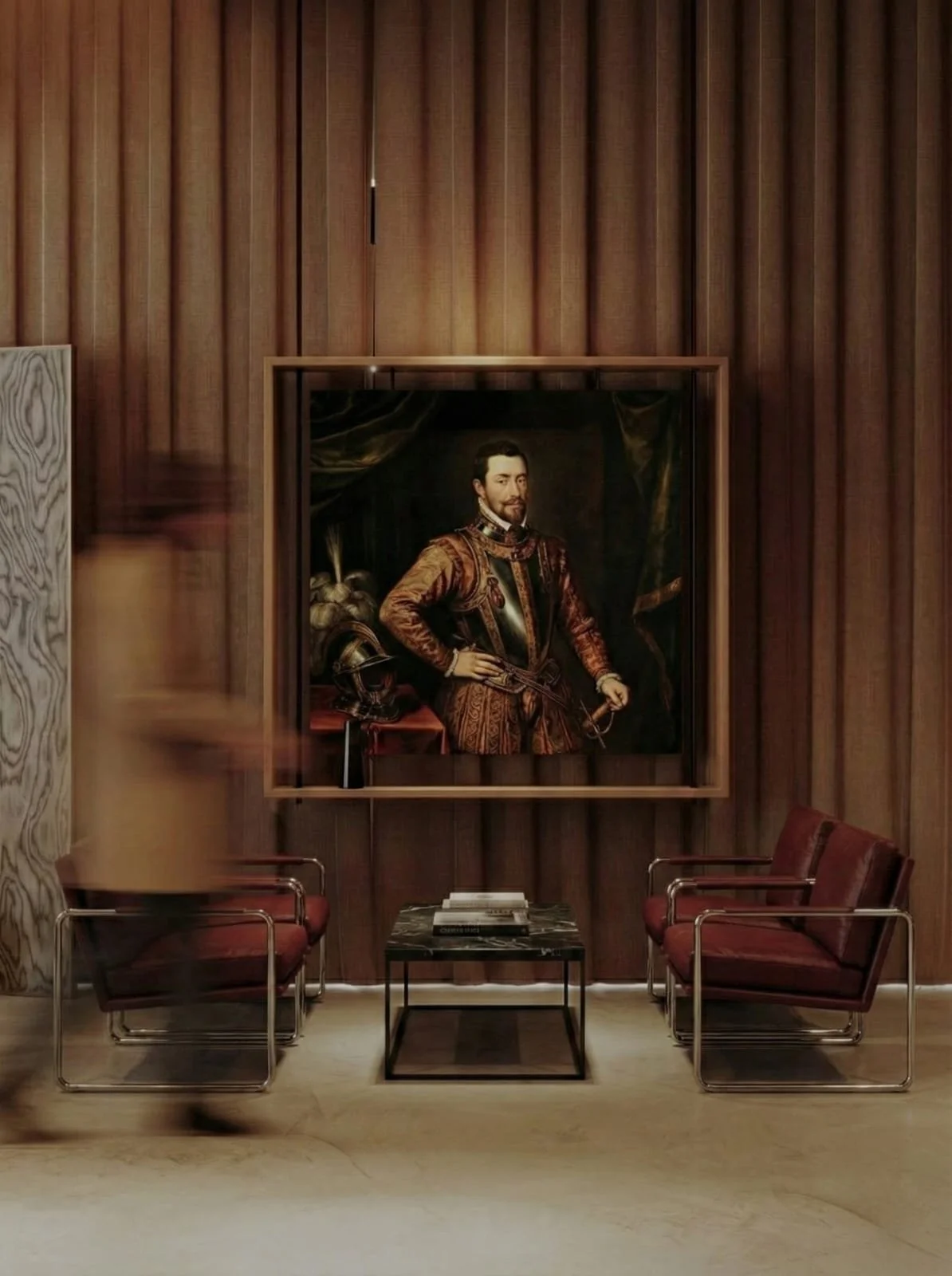 Sala con dos sillas y mesa de centro, en la pared un retrato de un hombre con vestimenta histórica.