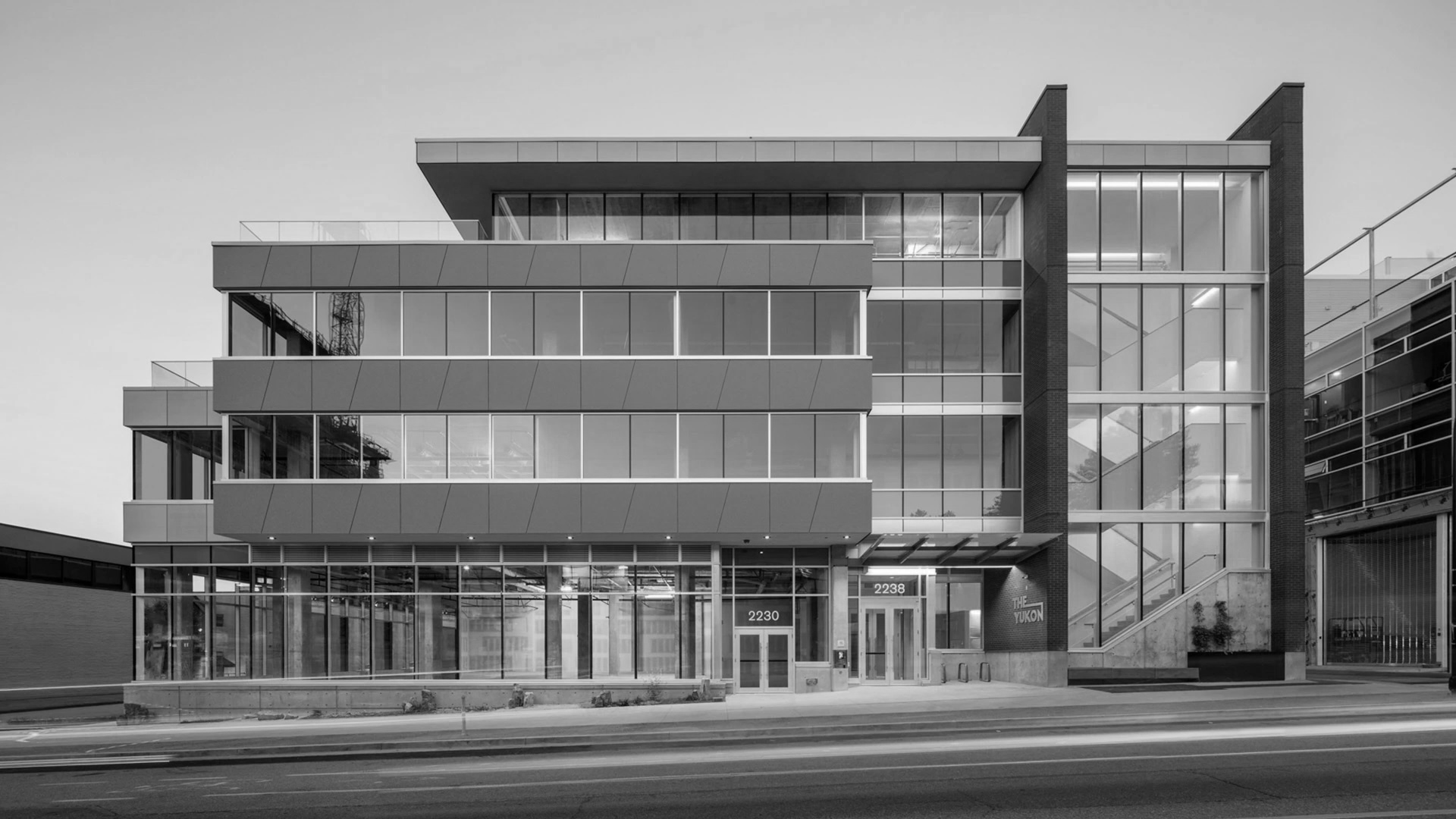 Modern multi-story office building with glass facade and signage 'The Yukon'.