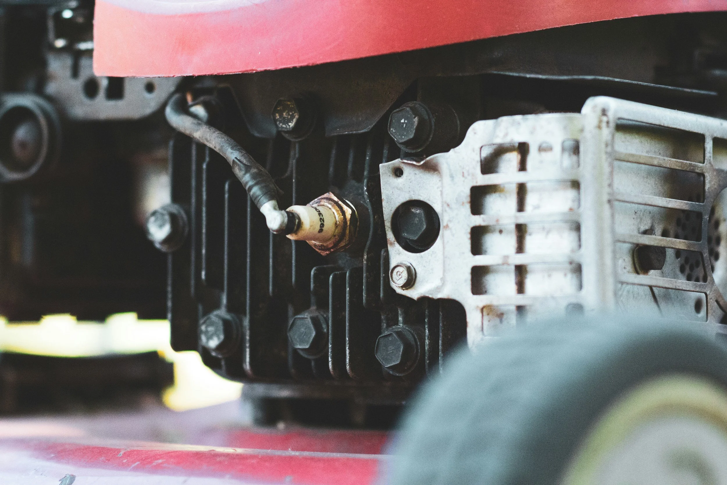 Close-up of mechanical machinery parts, including bolts, a spark plug, and metal components.