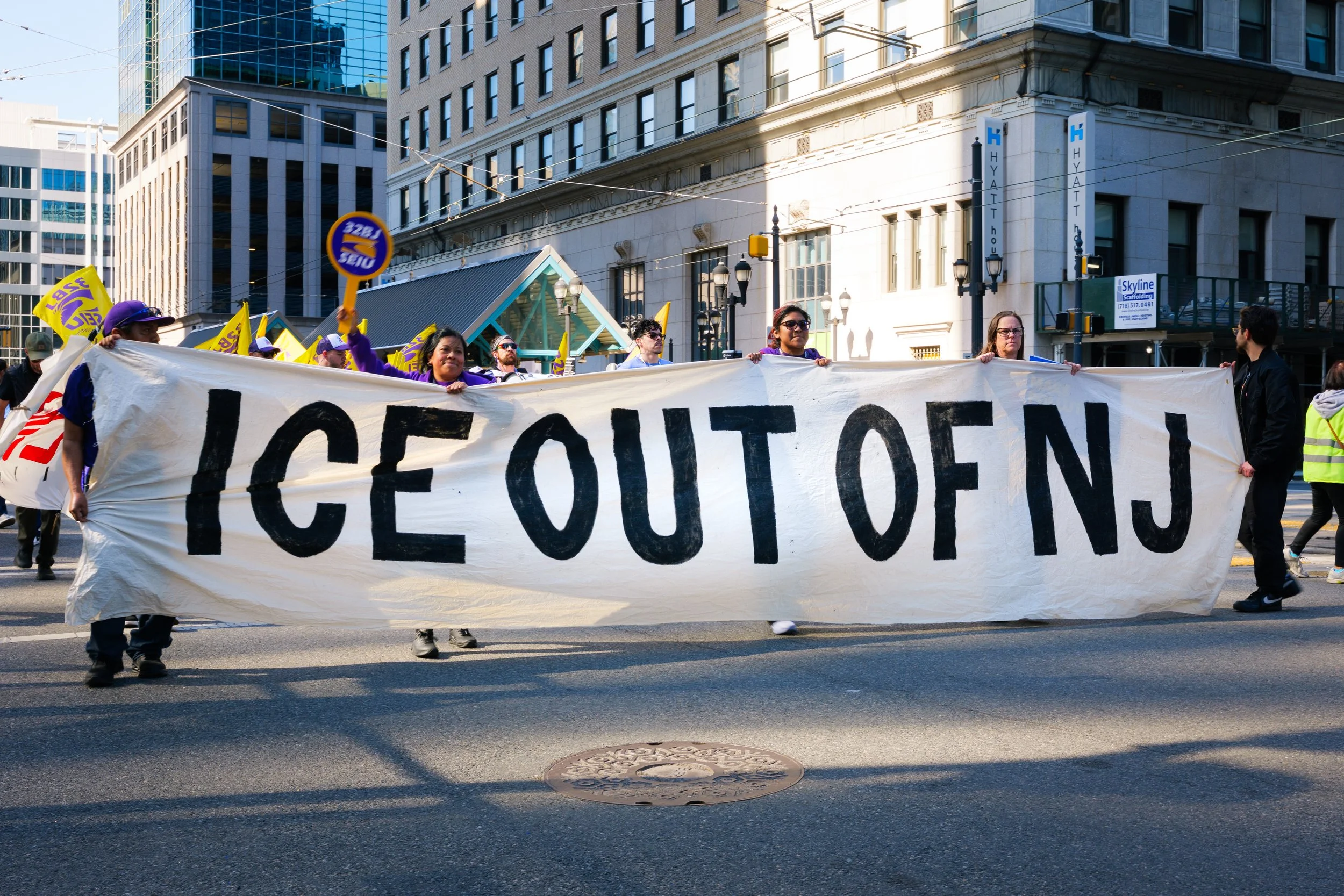 A banner held by marchers in downtown Jersey City states "ICE OUT OF NJ" as they approach the Goldman Sachs building