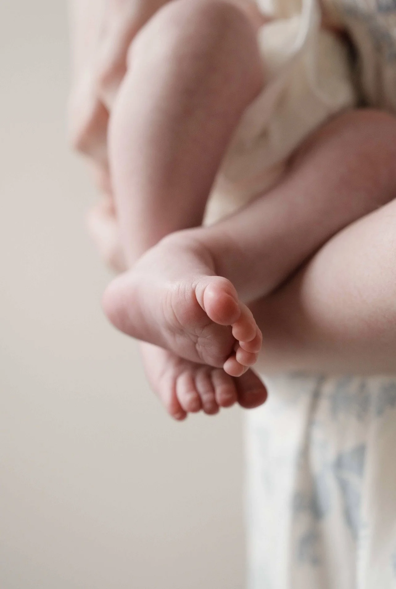 Close-up of a woman holding a small baby, focusing on the baby's tiny hand grasping the woman's finger.