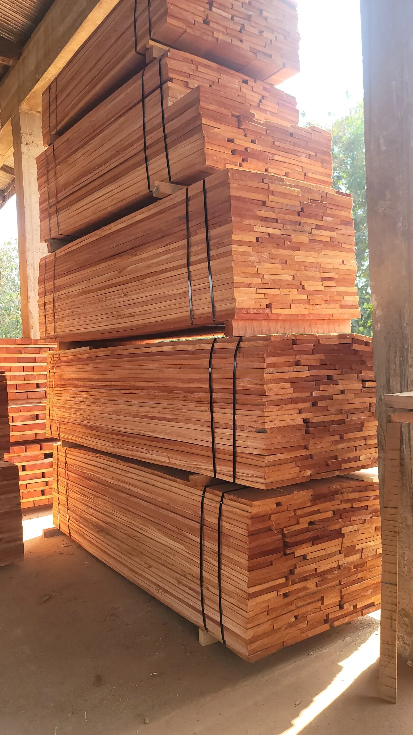 Stacks of wooden planks bundled together with black straps in a construction or storage area.