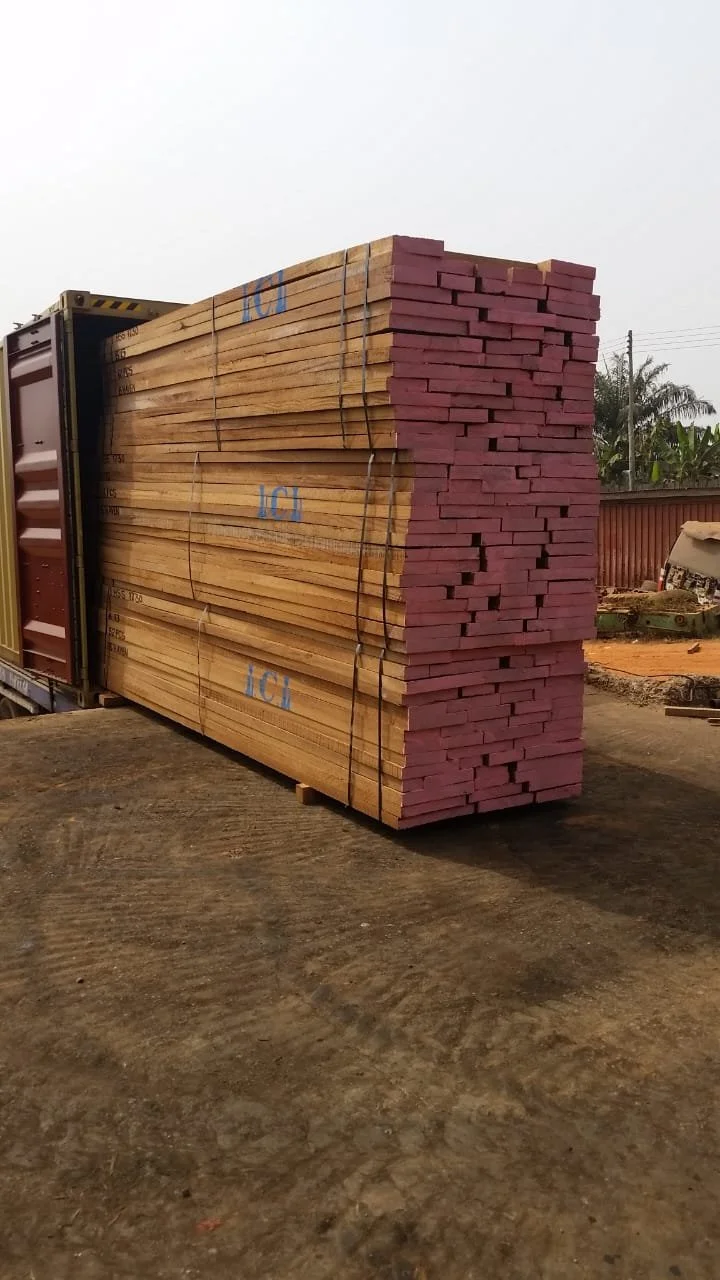 A large stack of wooden planks loaded into a shipping container on a construction site.