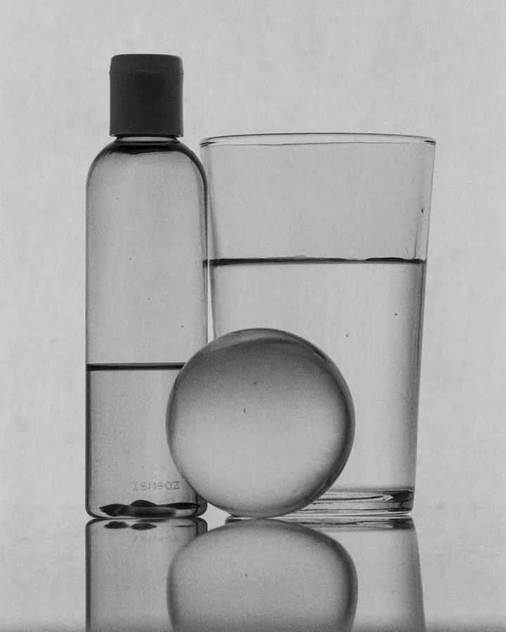 Editorial still life featuring a medicine bottle, tablet and glass of water, exploring themes of health, wellbeing and careful observation.