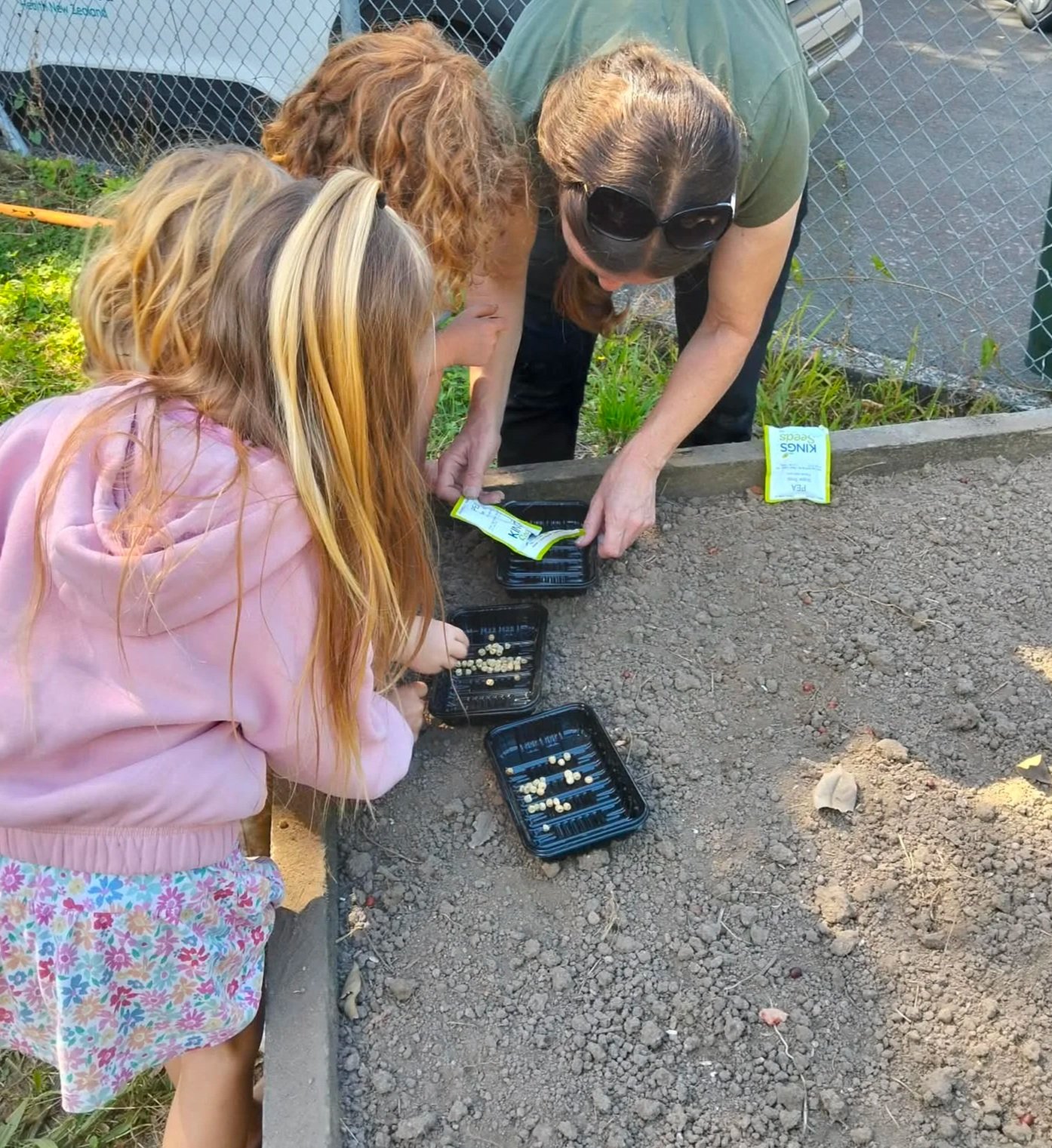 Children sowing seeds in the community garden bed