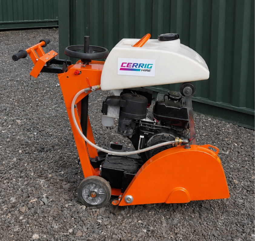 An orange and white floor cutting machine with a black handle and wheels, labeled 'CERRIG HIRE', on gravel ground with a green corrugated metal wall in the background.