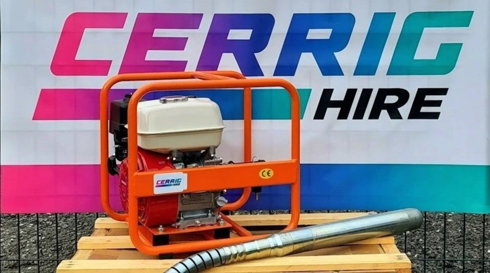 Portable water pump with orange frame and white engine, placed on a wooden pallet in front of a Cerrig Hire banner.