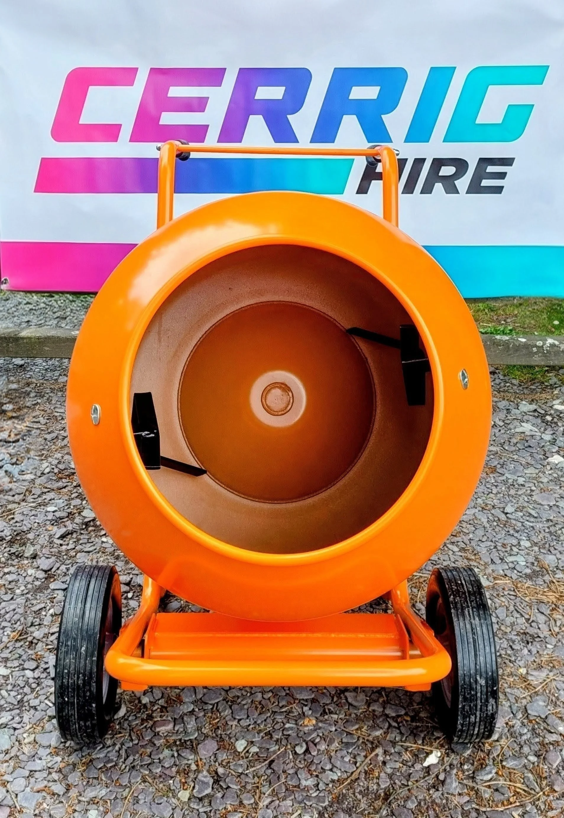 Orange cement mixer on gravel ground with a colorful banner in the background