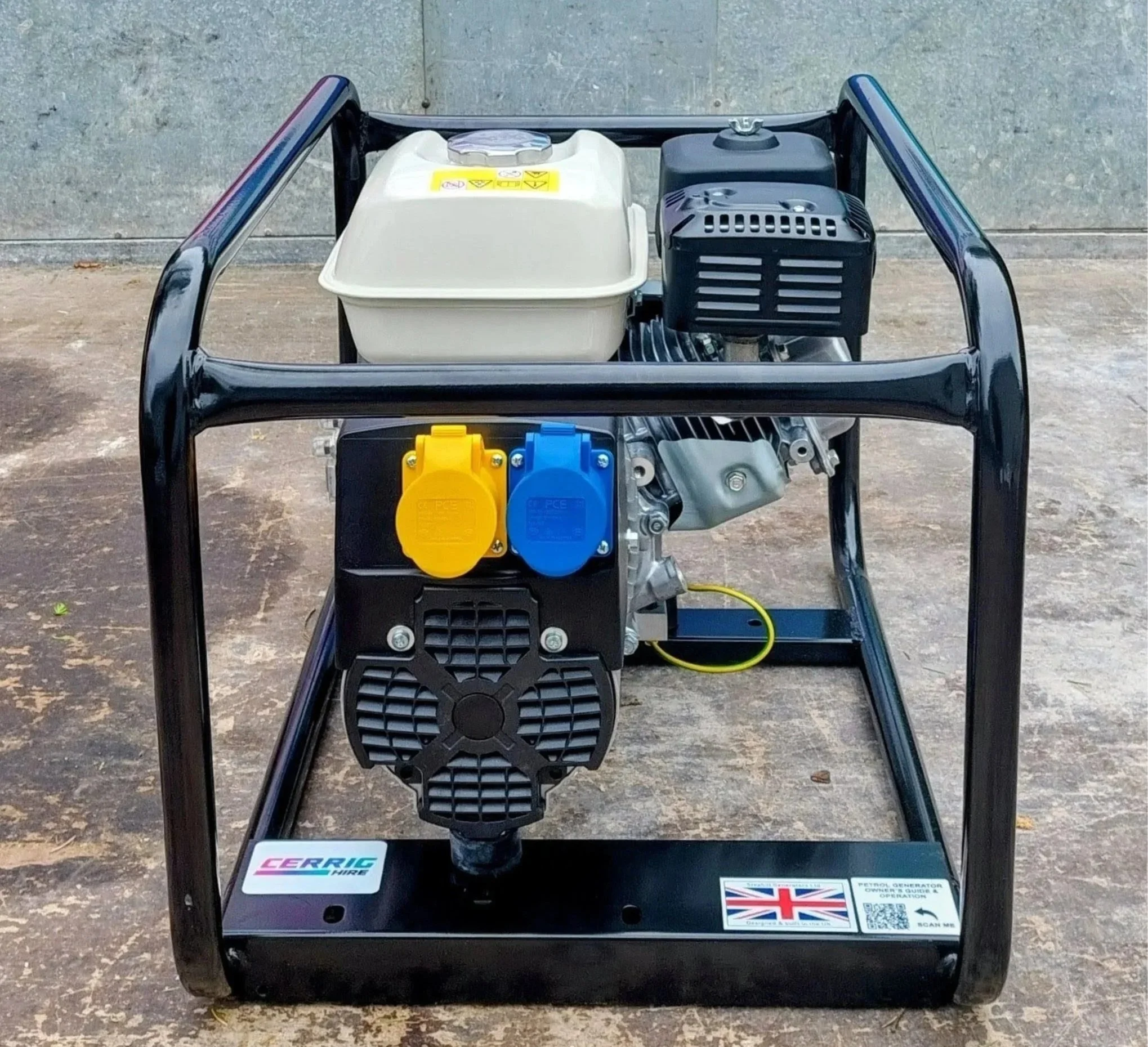 Front view of a portable generator with black frame, white and black engine components, colored power outlets, and stickers, placed on a ground surface against a concrete wall.