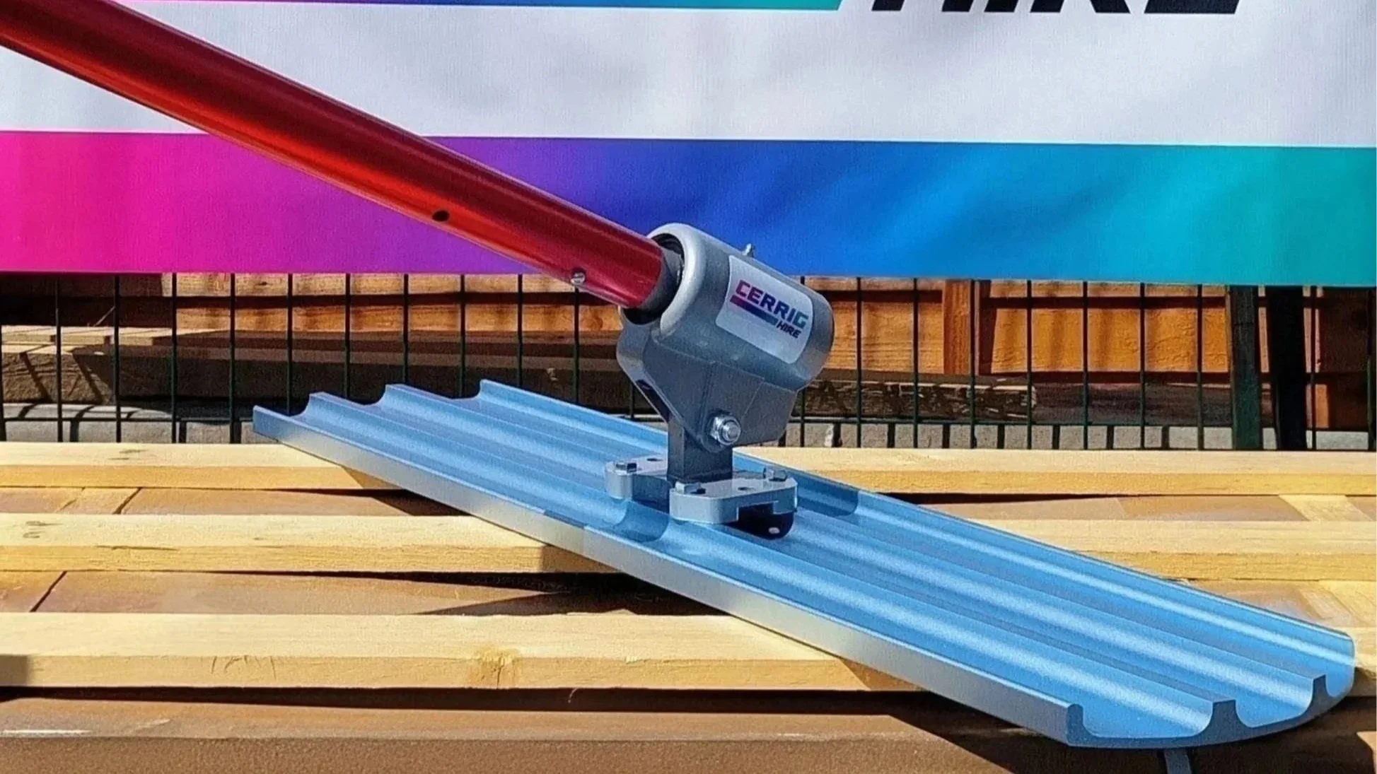 A red and gray concrete float, with a background of a wooden fence and a multicolored banner.