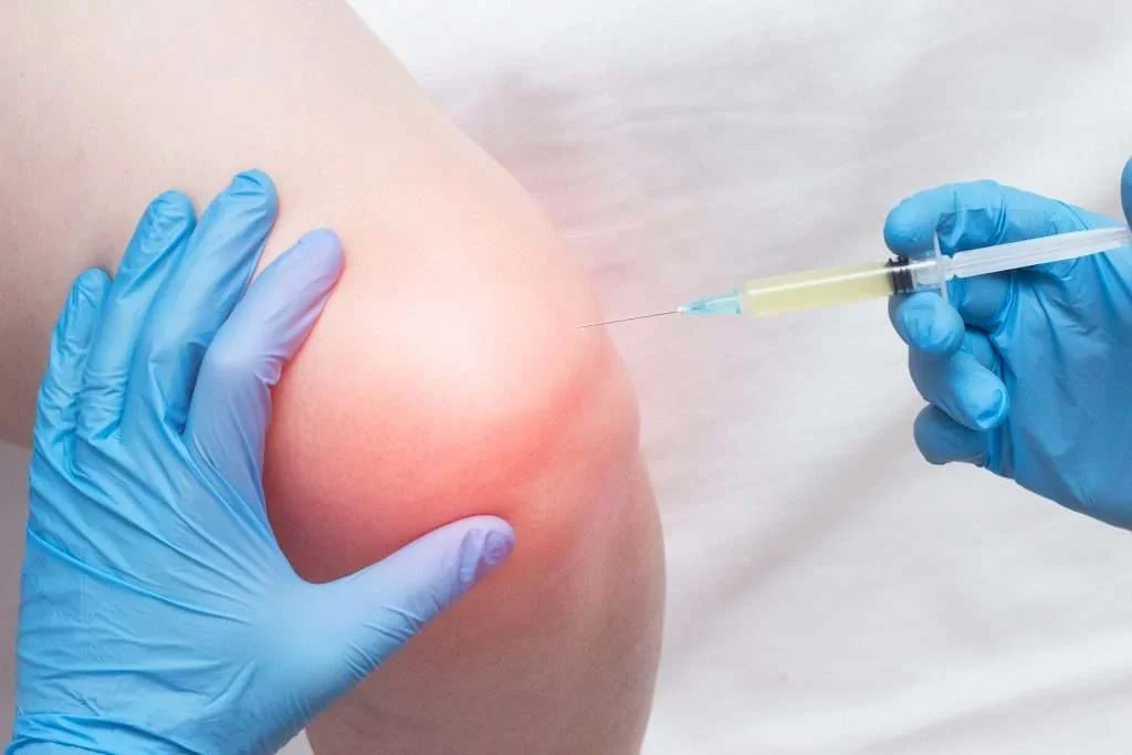 A person receiving a vaccination shot in their upper arm, administered by a healthcare professional wearing blue gloves.